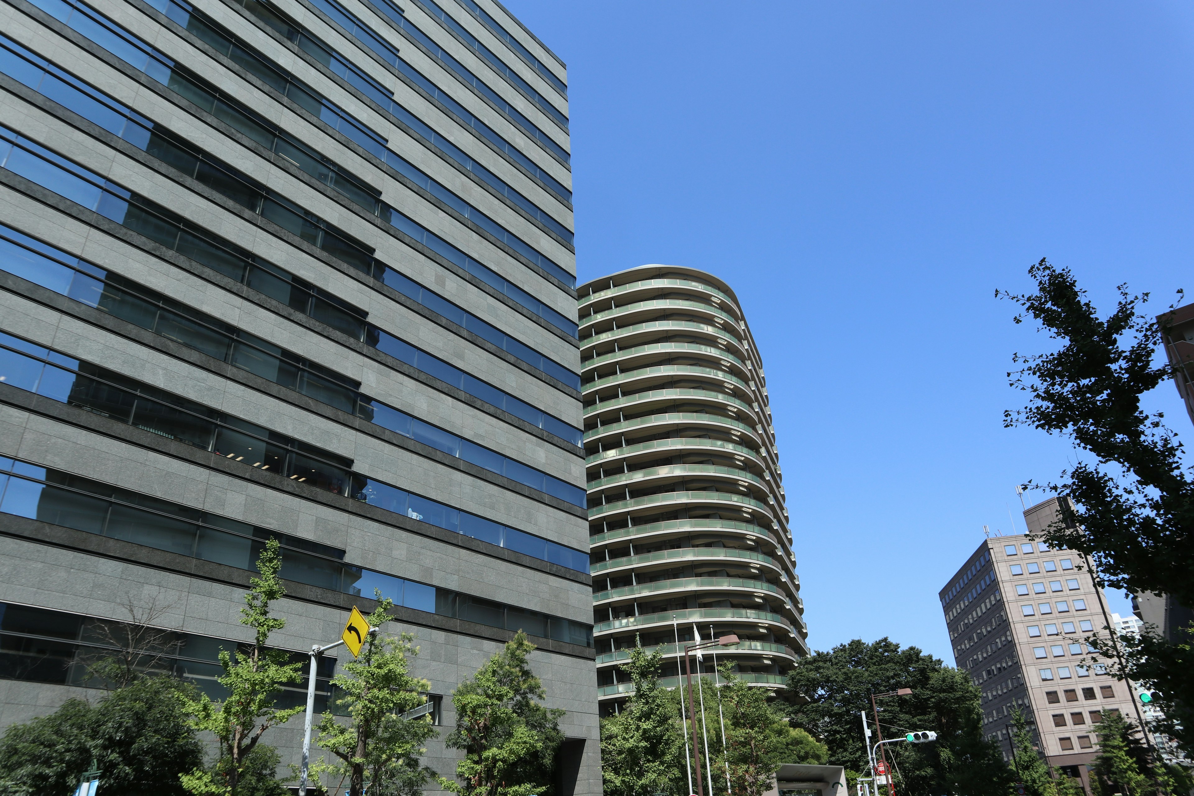 Urban landscape featuring high-rise buildings and a round structure under a clear blue sky