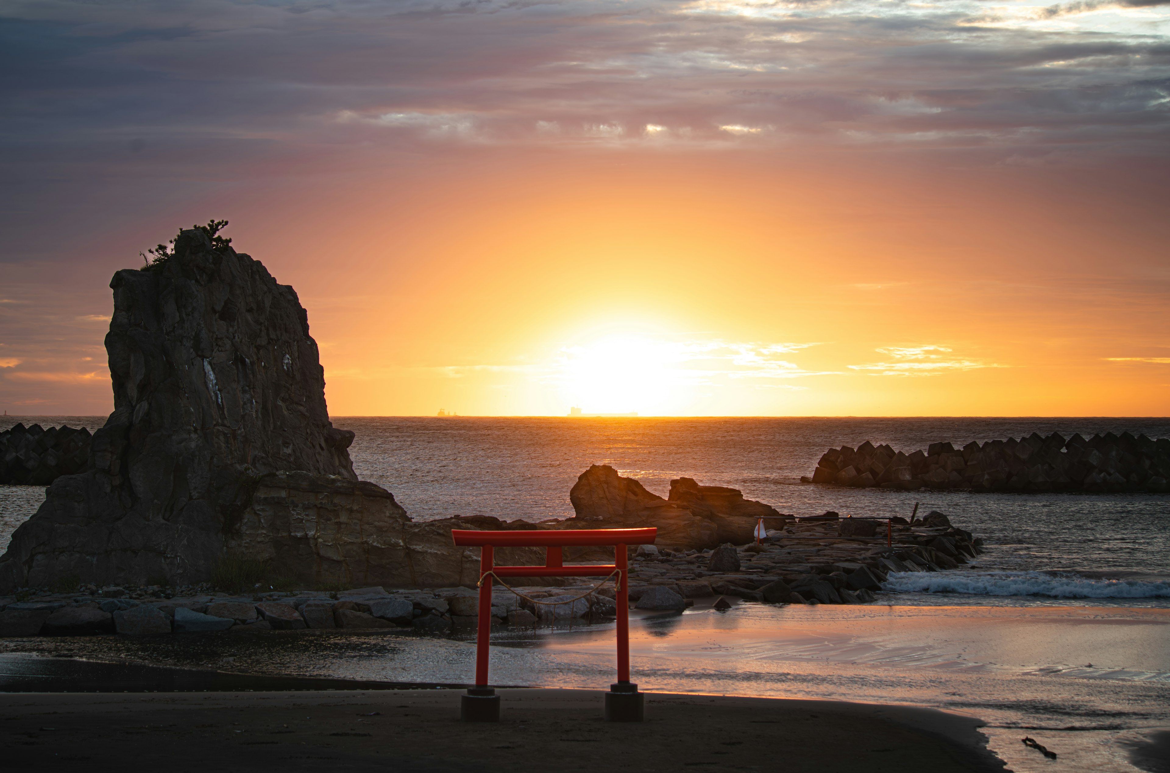 Vue panoramique d'un torii rouge et d'un rocher au coucher de soleil