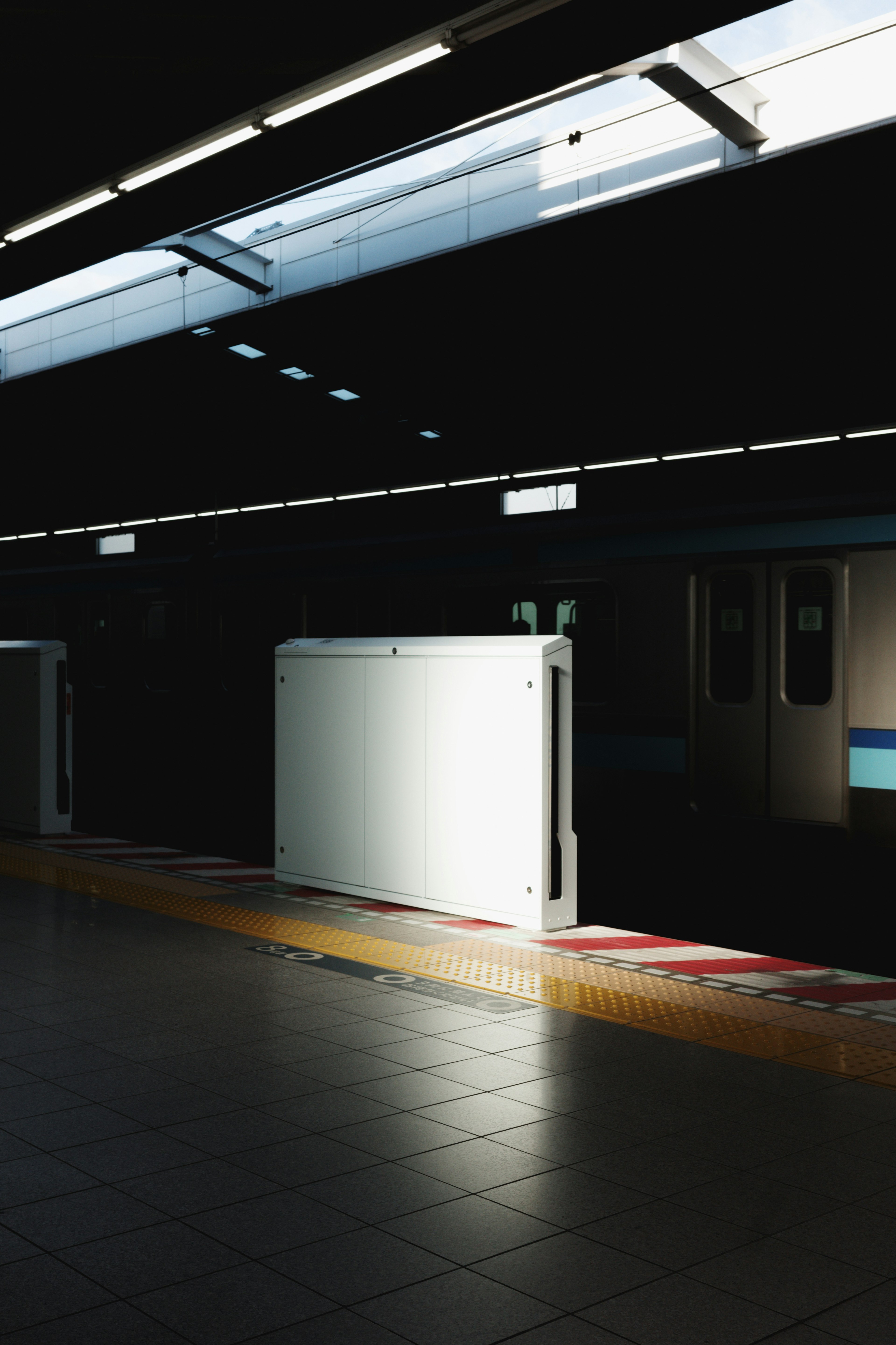 Contraste de una puerta blanca en una plataforma de metro oscura con luz natural