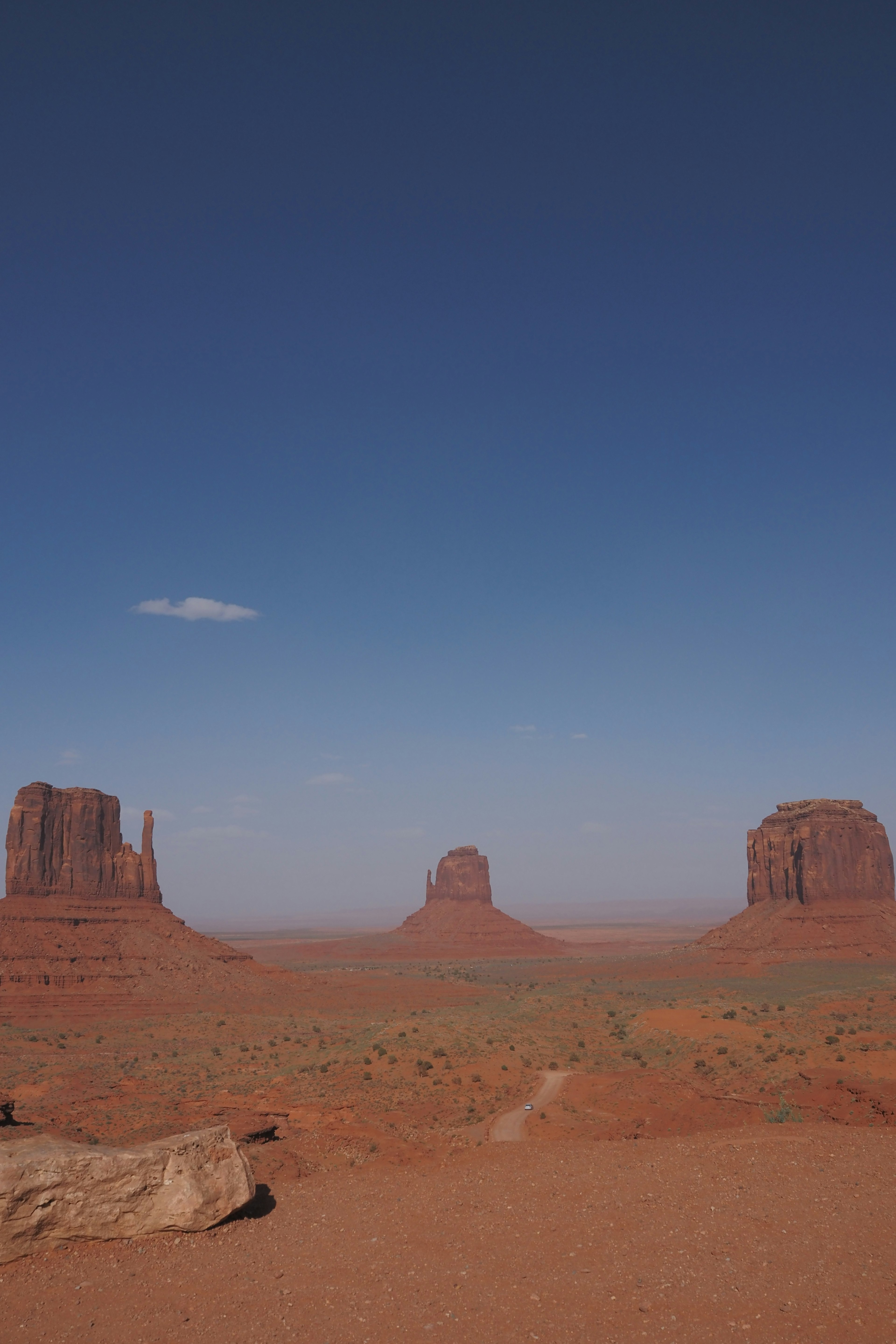 Vast landscape of Monument Valley Red sandy terrain and rock formations Blue sky