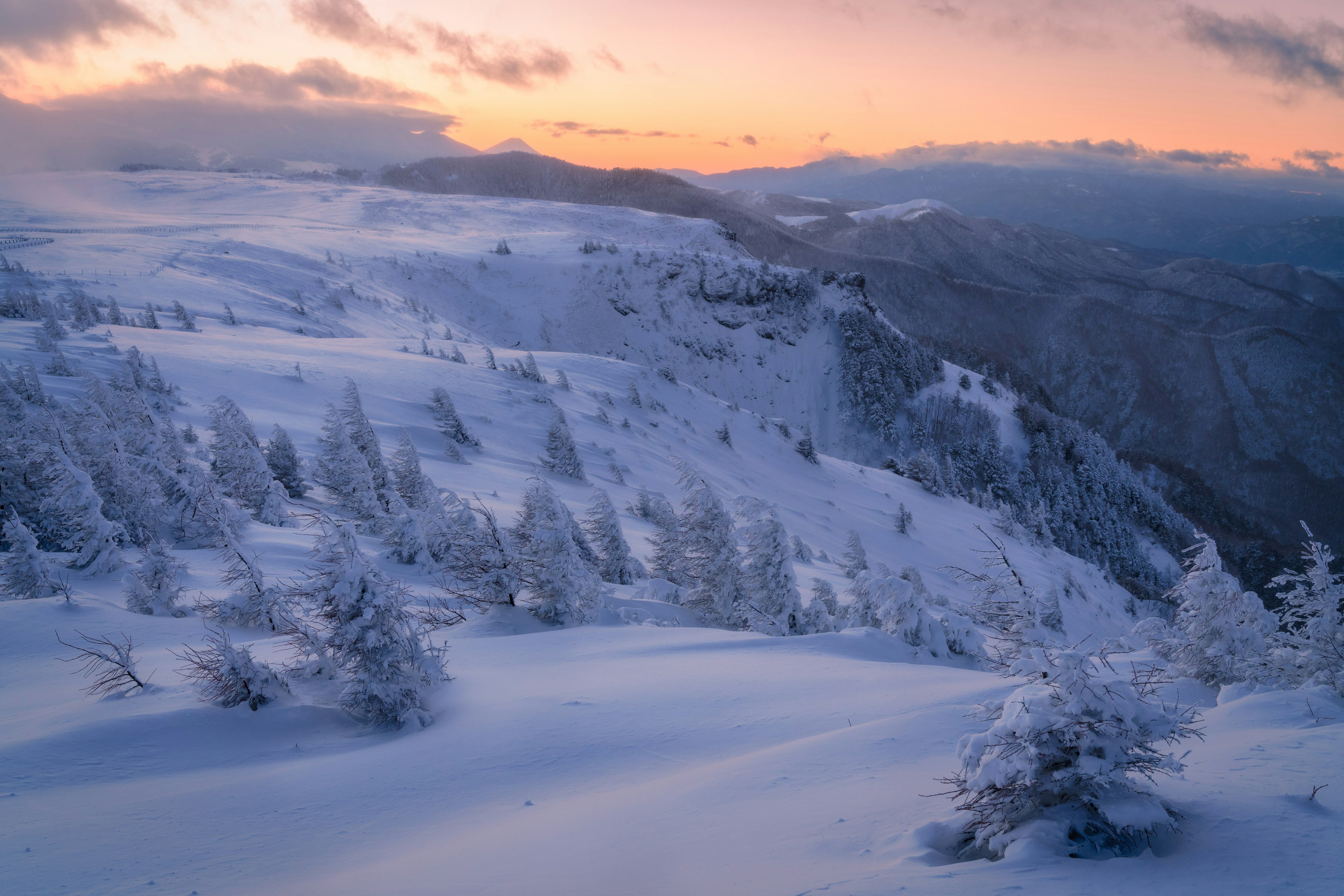 Snow-covered mountain landscape with sunset sky