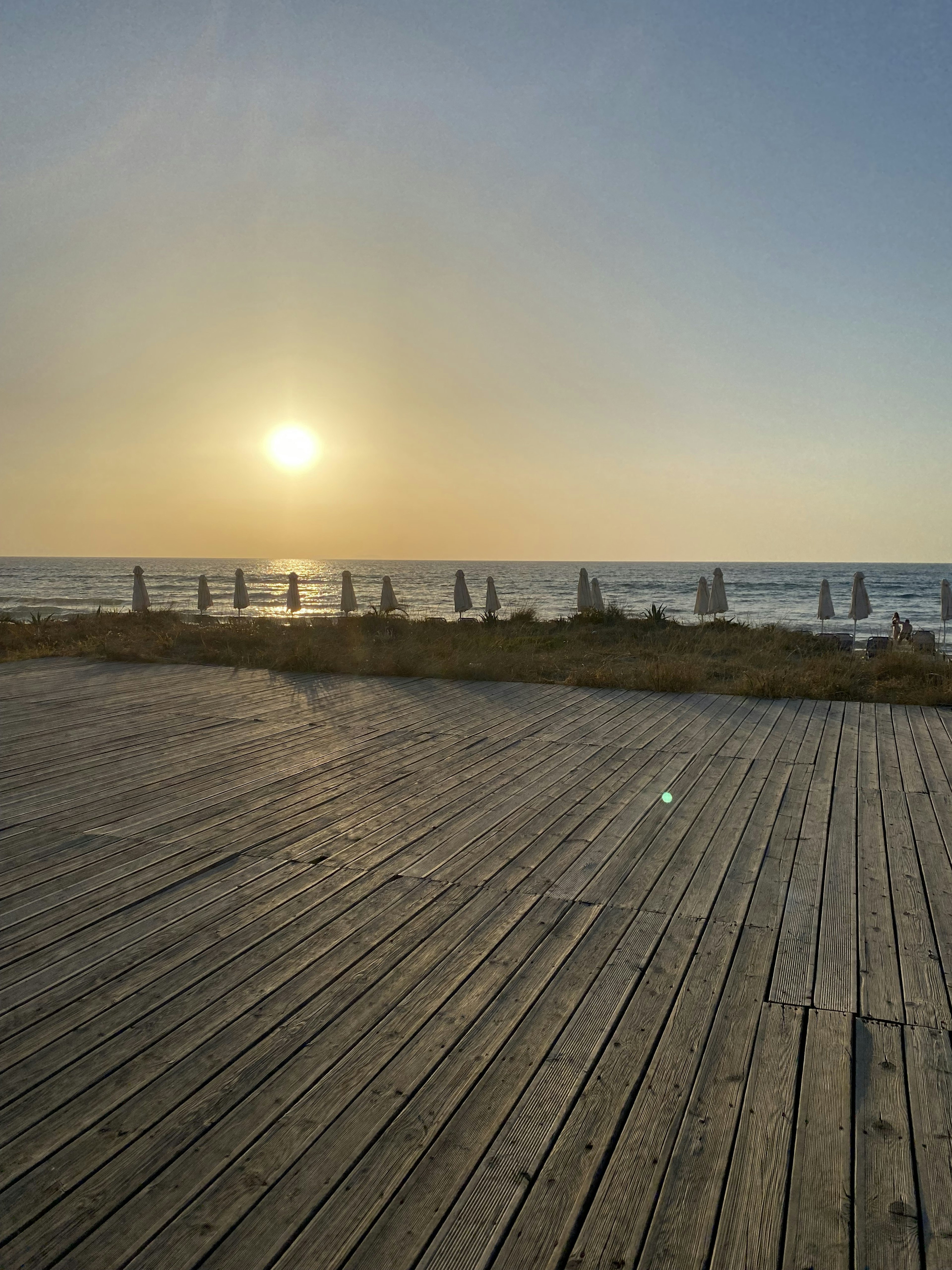 Terrasse en bois surplombant l'océan avec un coucher de soleil