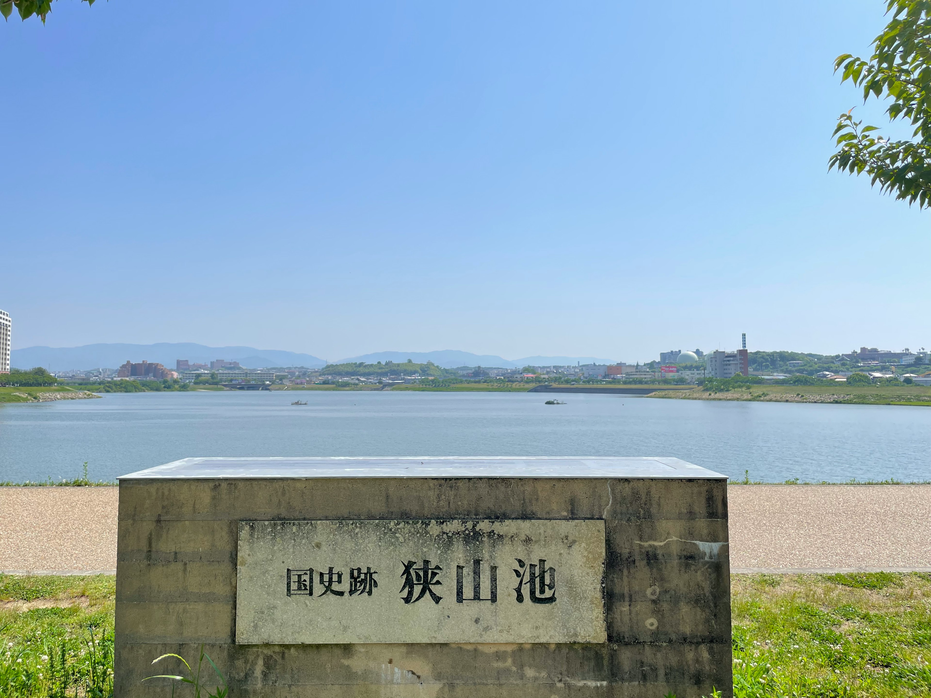 池の名前が書かれた石碑と青い空の下の風景