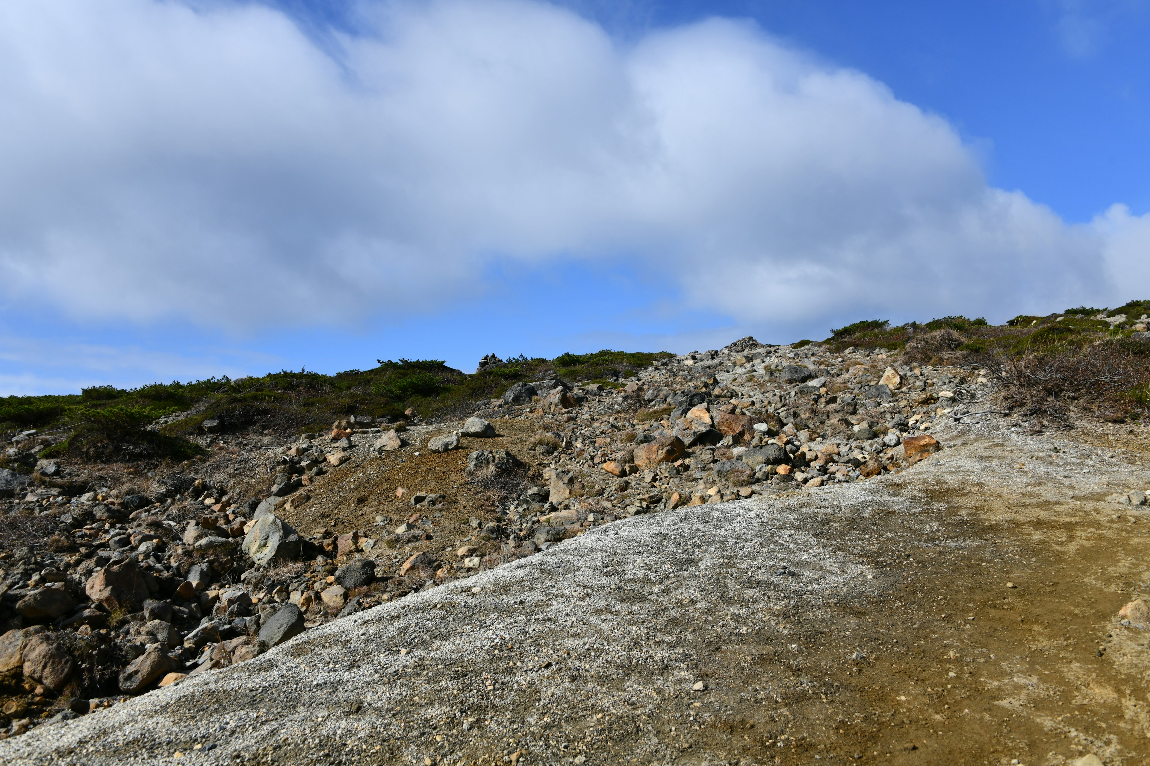 Hügellandschaft mit verstreuten Steinen und grüner Vegetation