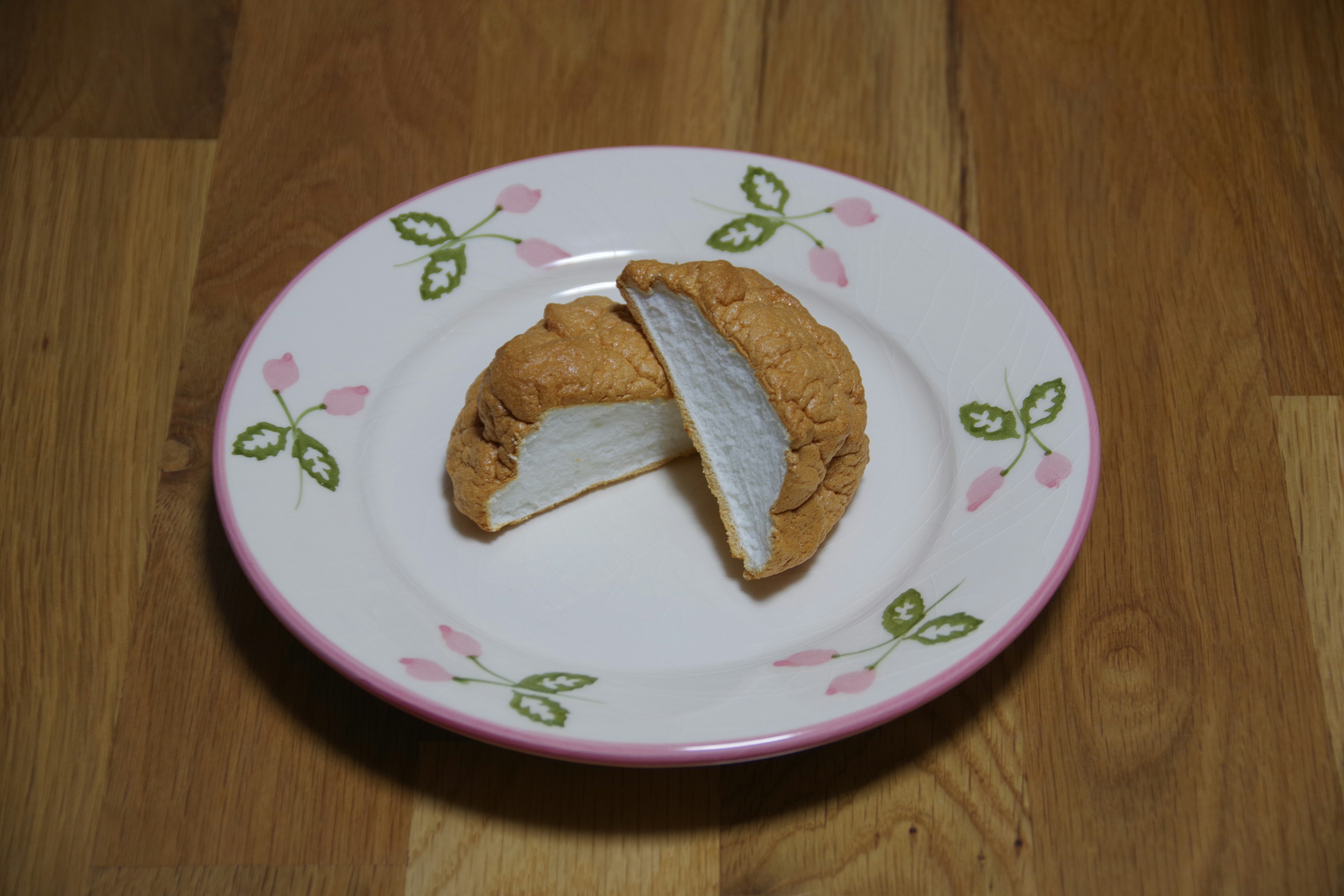 A half-cut cookie with a white filling on a floral plate