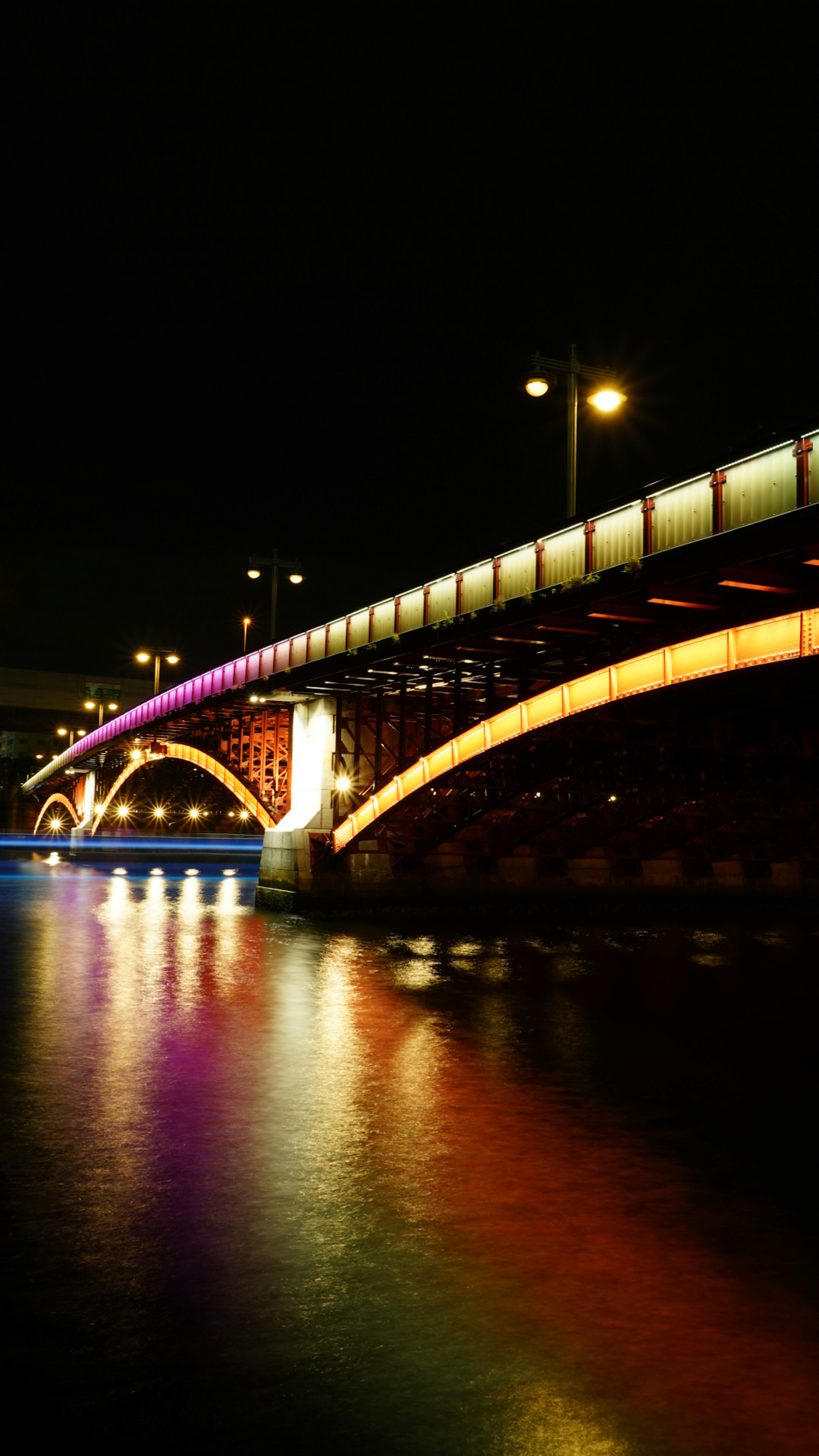 Beautifully illuminated bridge at night with colorful reflections