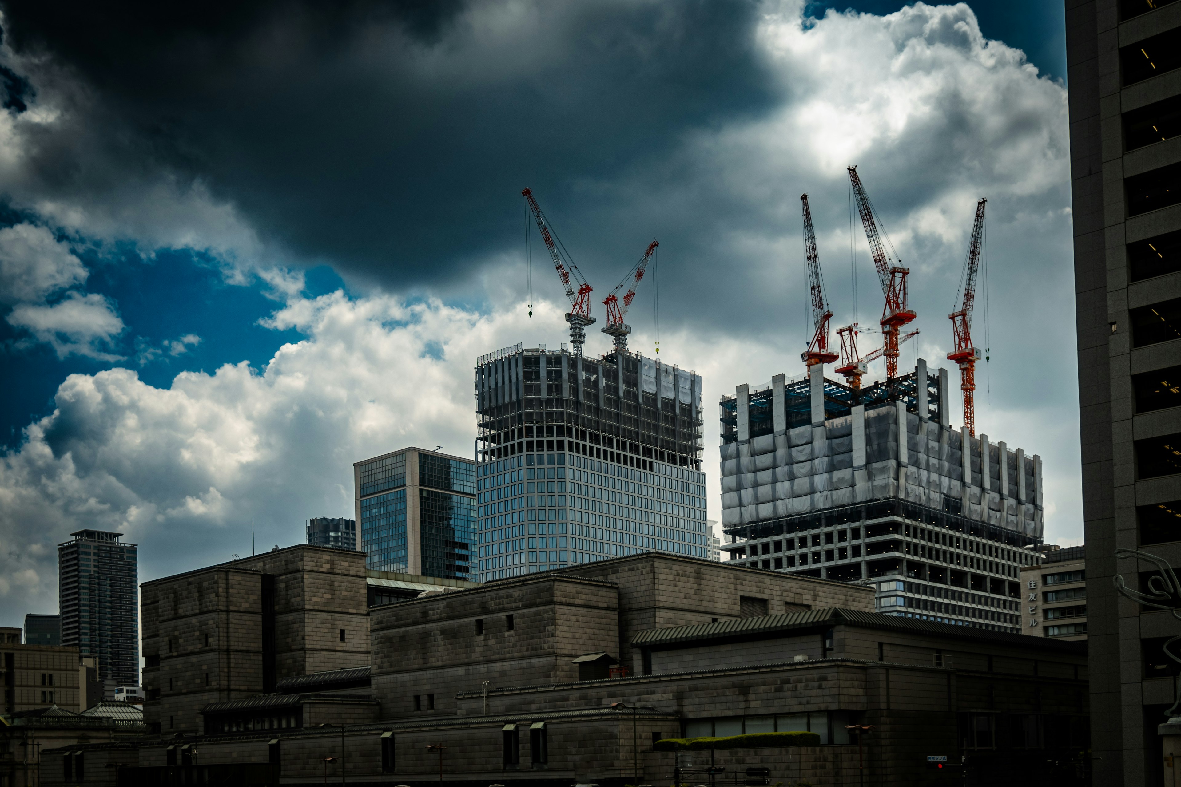 Urban skyline featuring construction sites with cranes and dark clouds