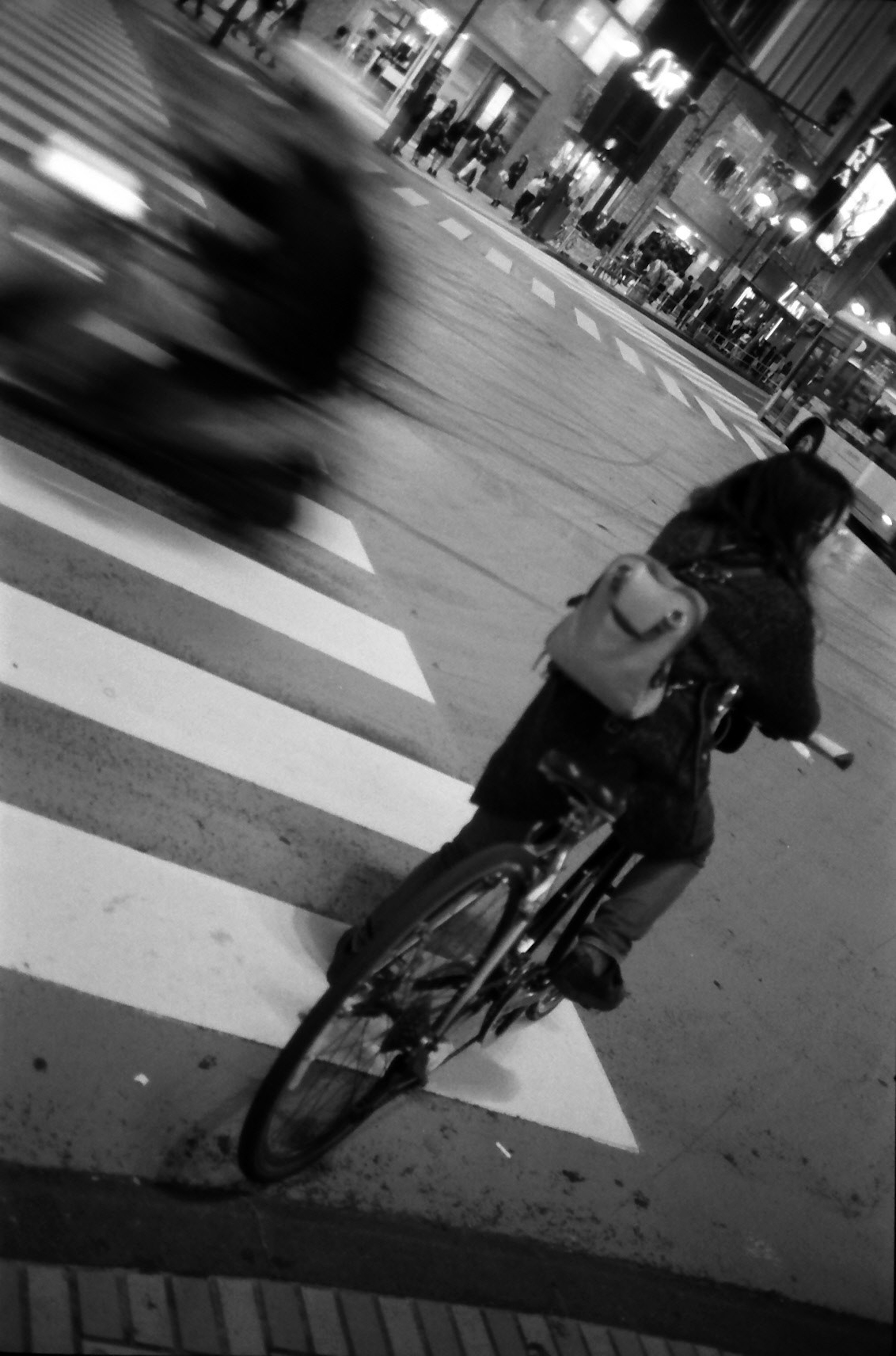 Person on bicycle at night intersection with blurred cars