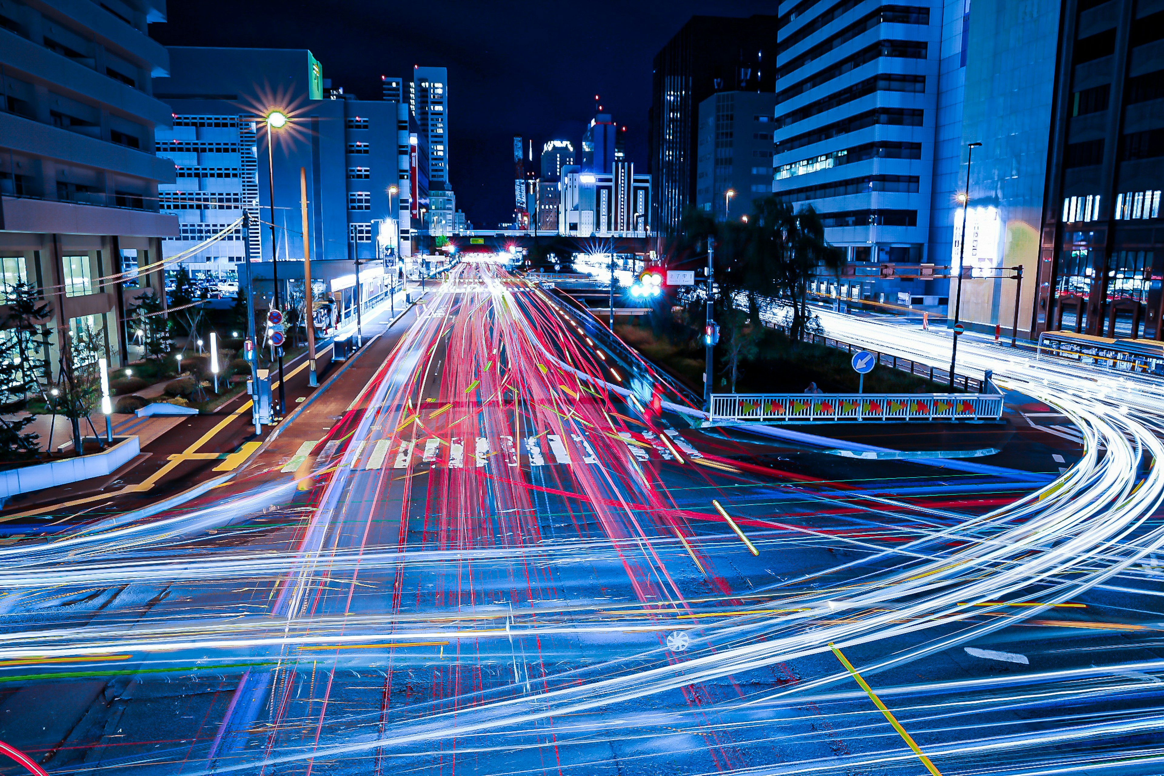 Beeindruckende Lichtspuren von Autos an einer Kreuzung in einer nächtlichen Stadtlandschaft