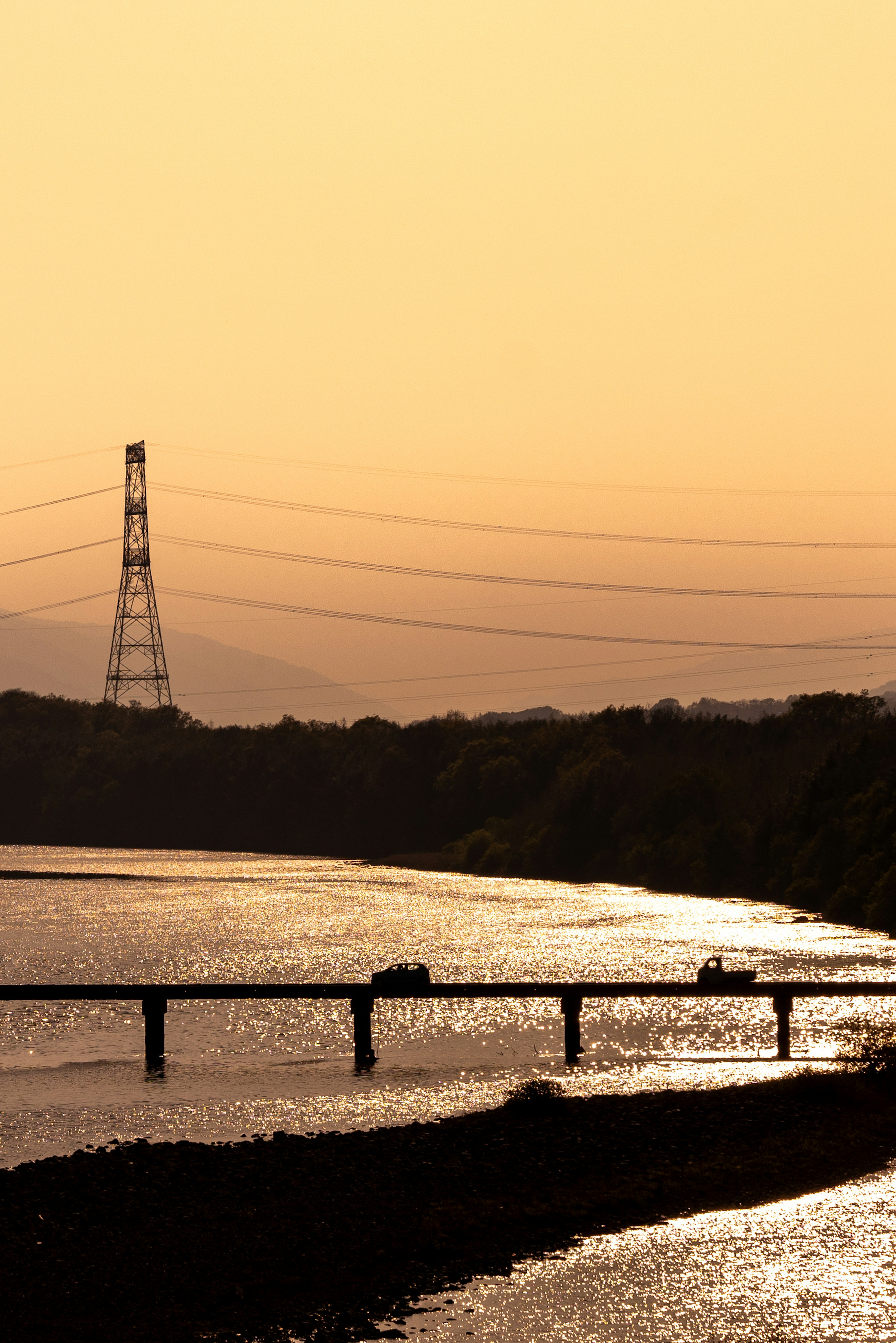 川の流れと夕焼けの空に映る電柱と橋の風景