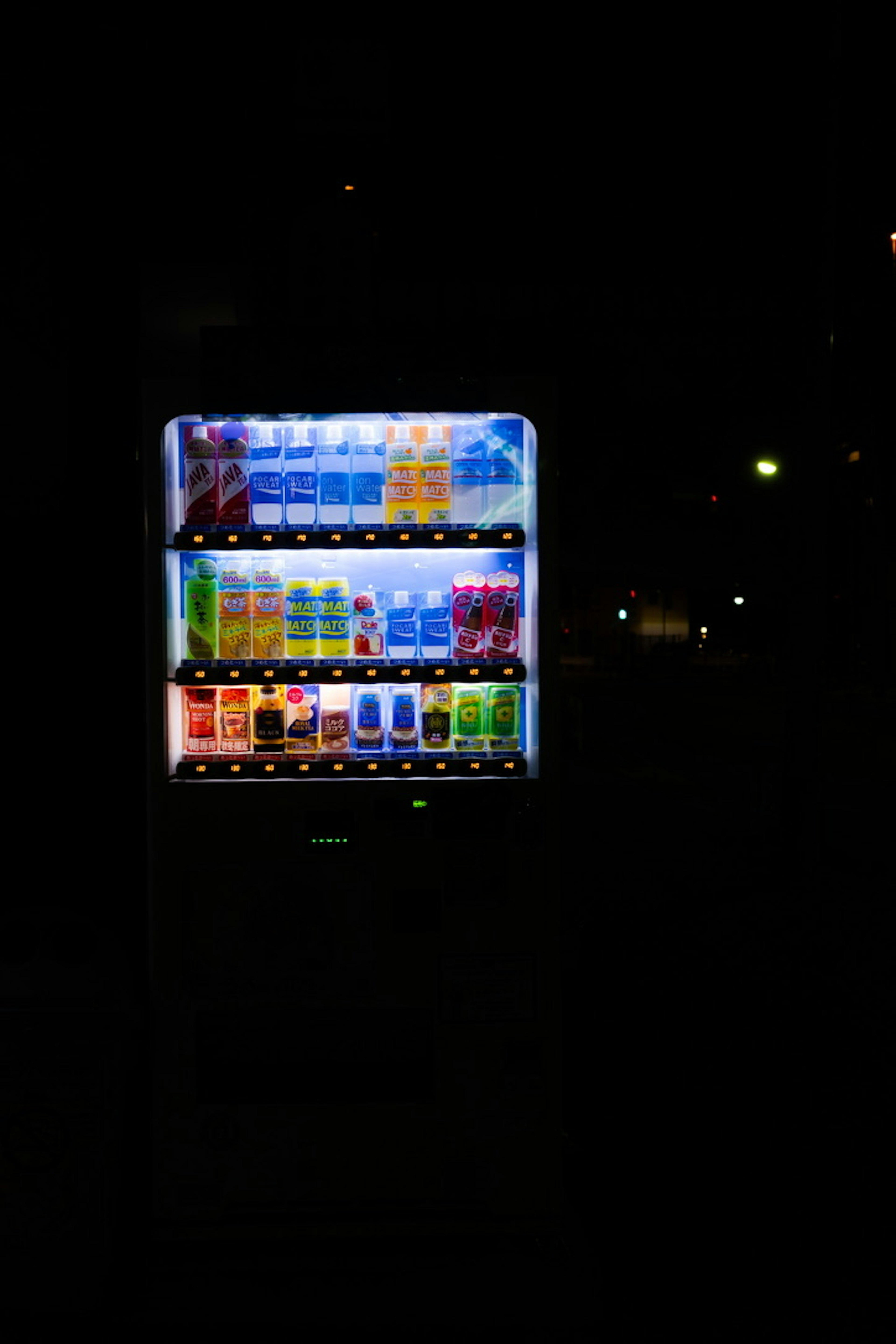 Illuminated vending machine displaying various colorful drinks at night