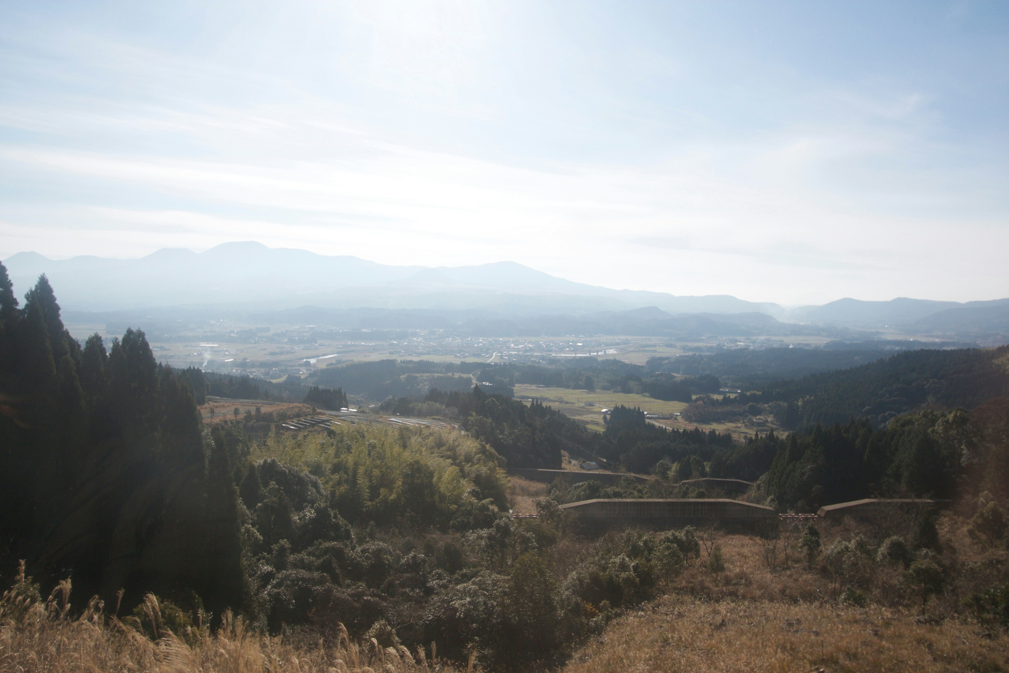 A panoramic view of green valleys surrounded by mountains under a blue sky