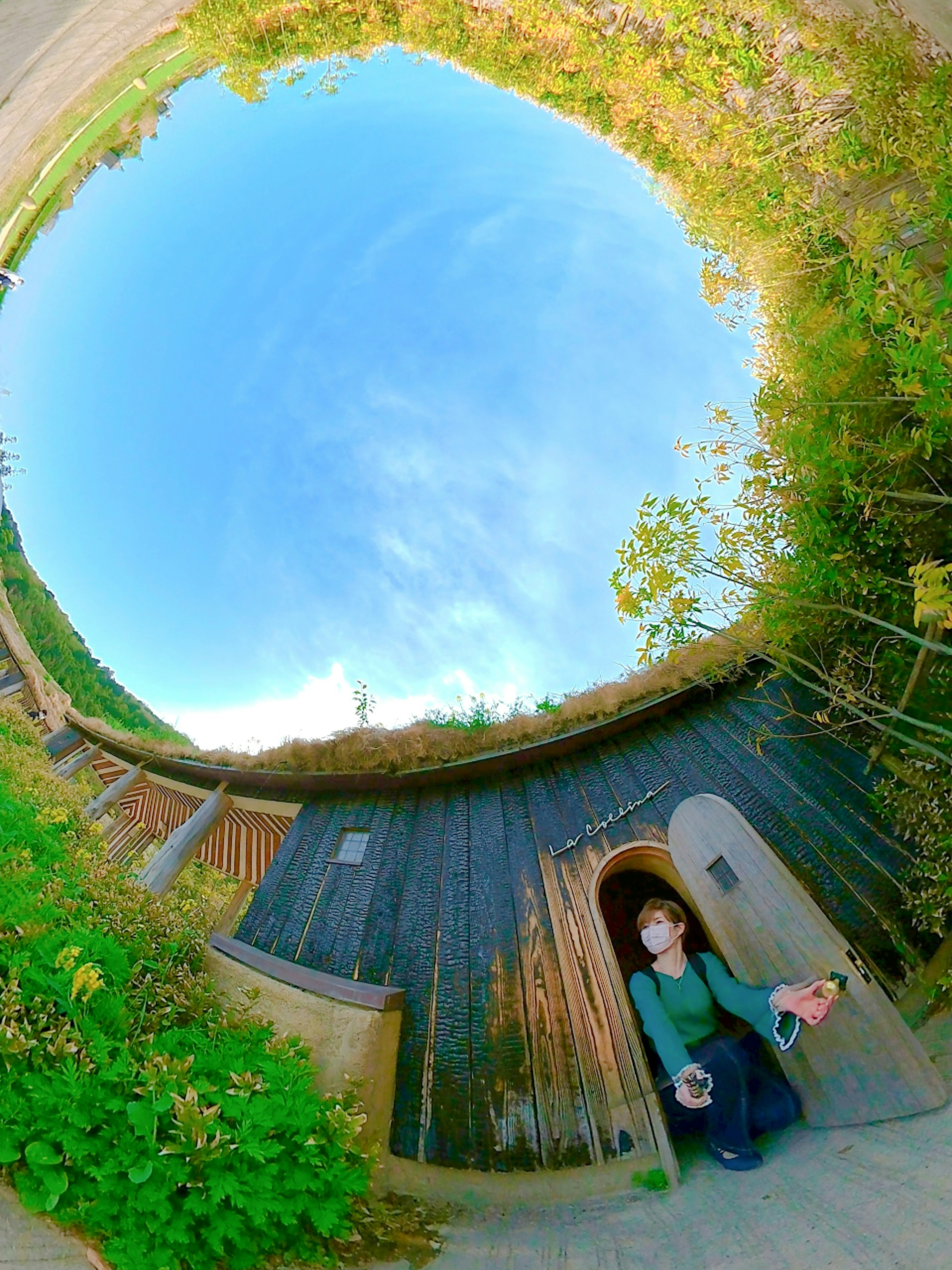 A wooden hut under a blue sky with a person sitting in front