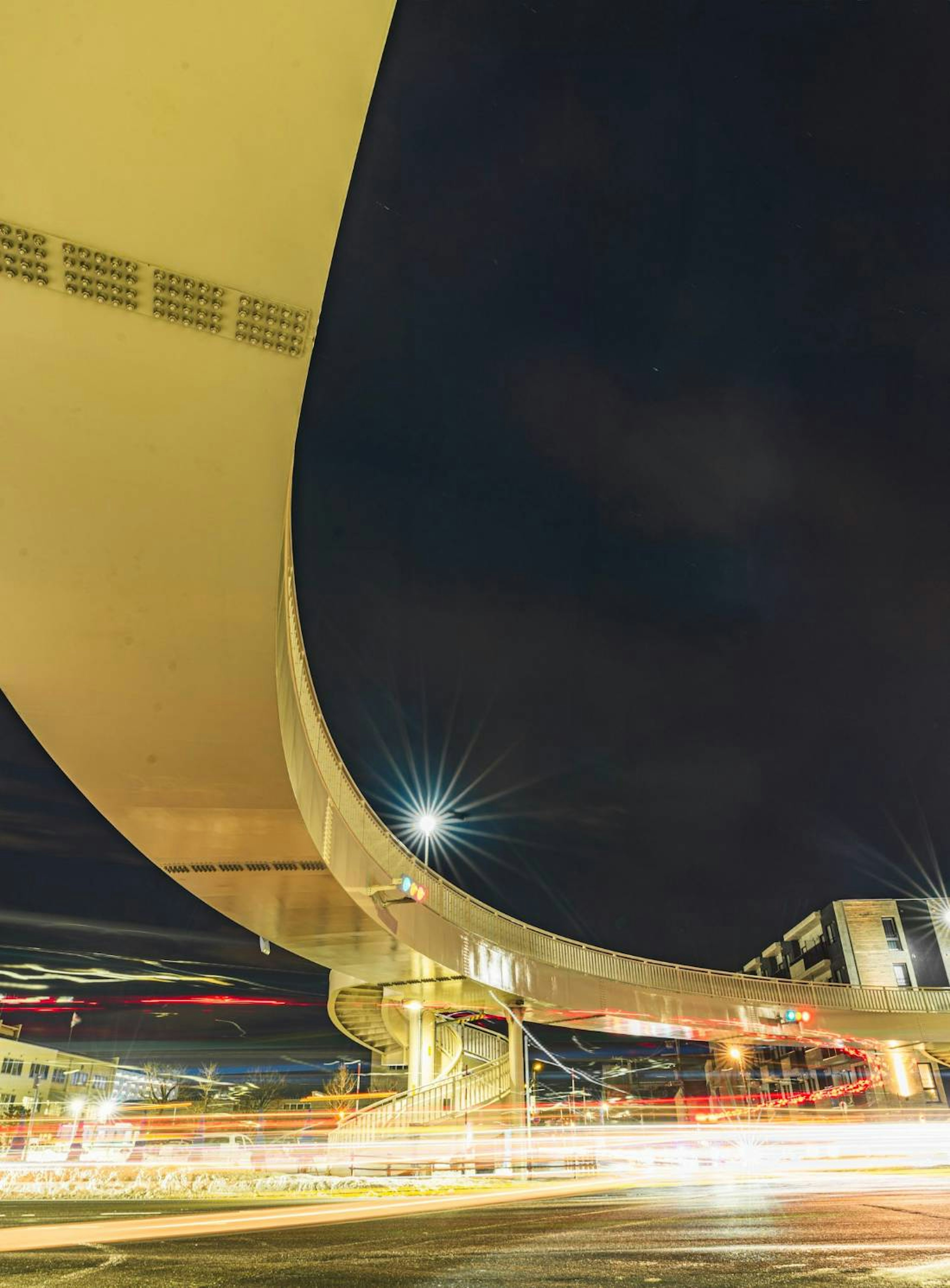 Viadotto curvo in un paesaggio urbano notturno con luci di auto