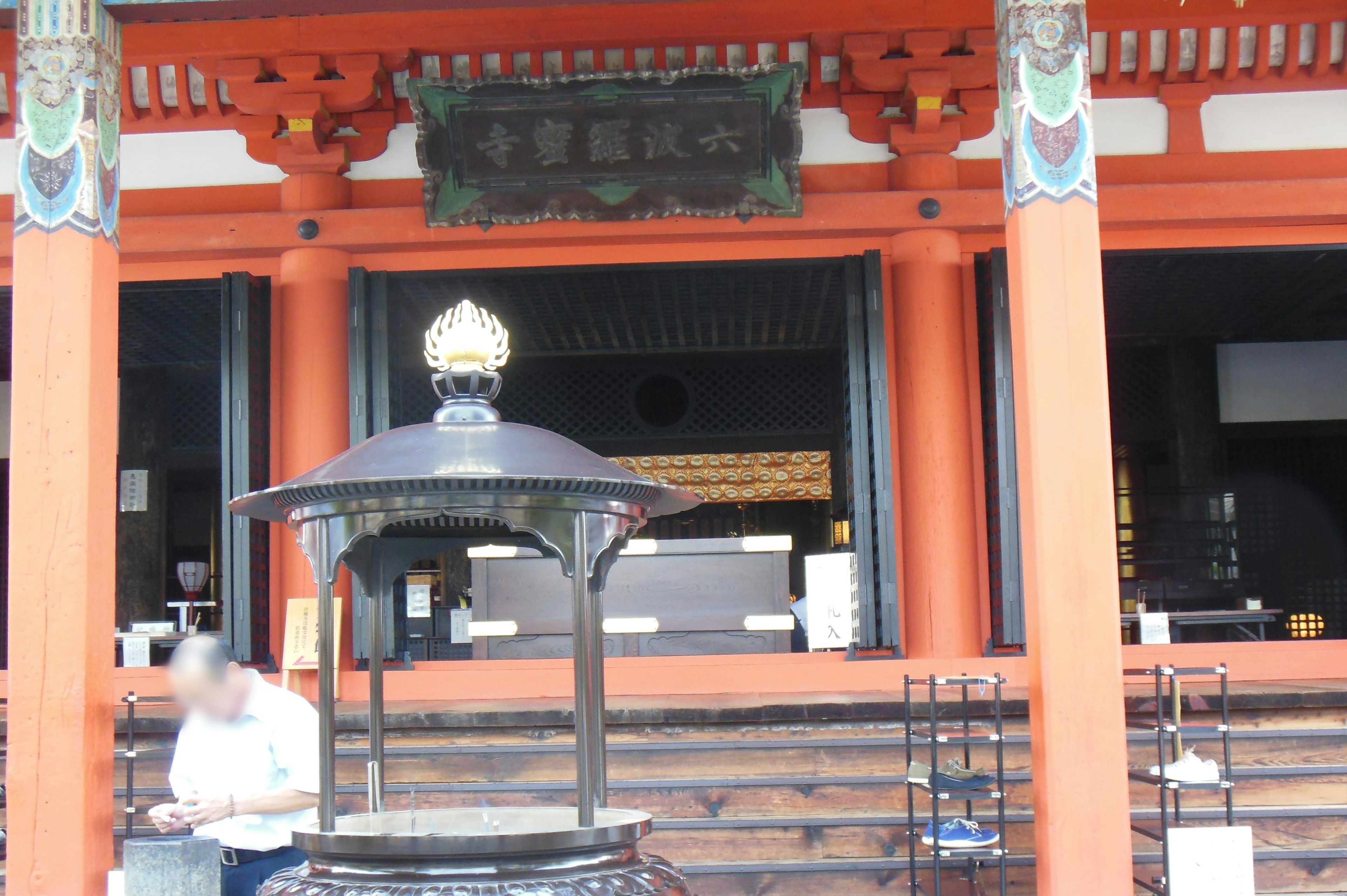 Entrance of a Japanese shrine with red pillars and decorative roof featuring a water basin