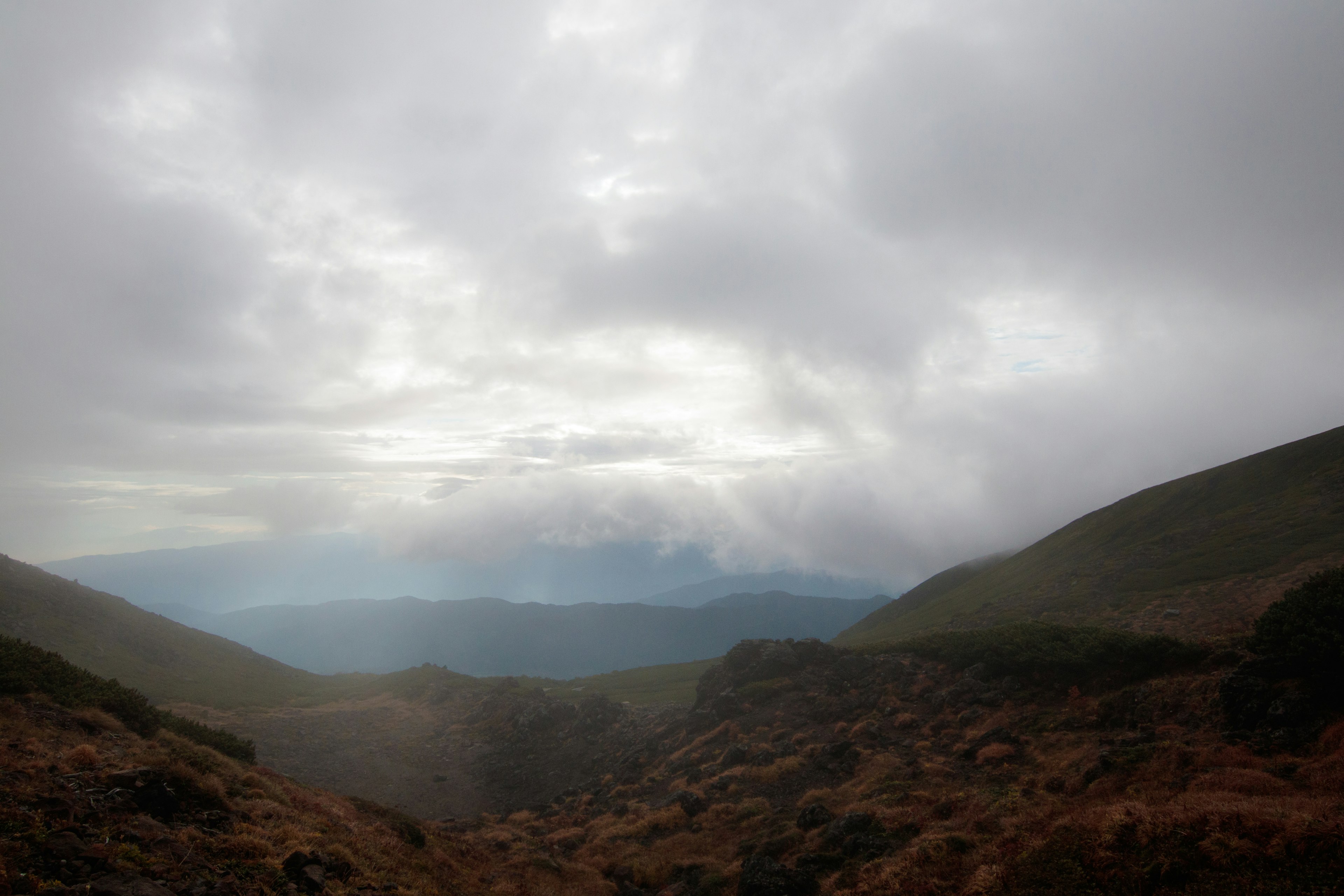 Mountainous landscape with valleys under a cloudy sky