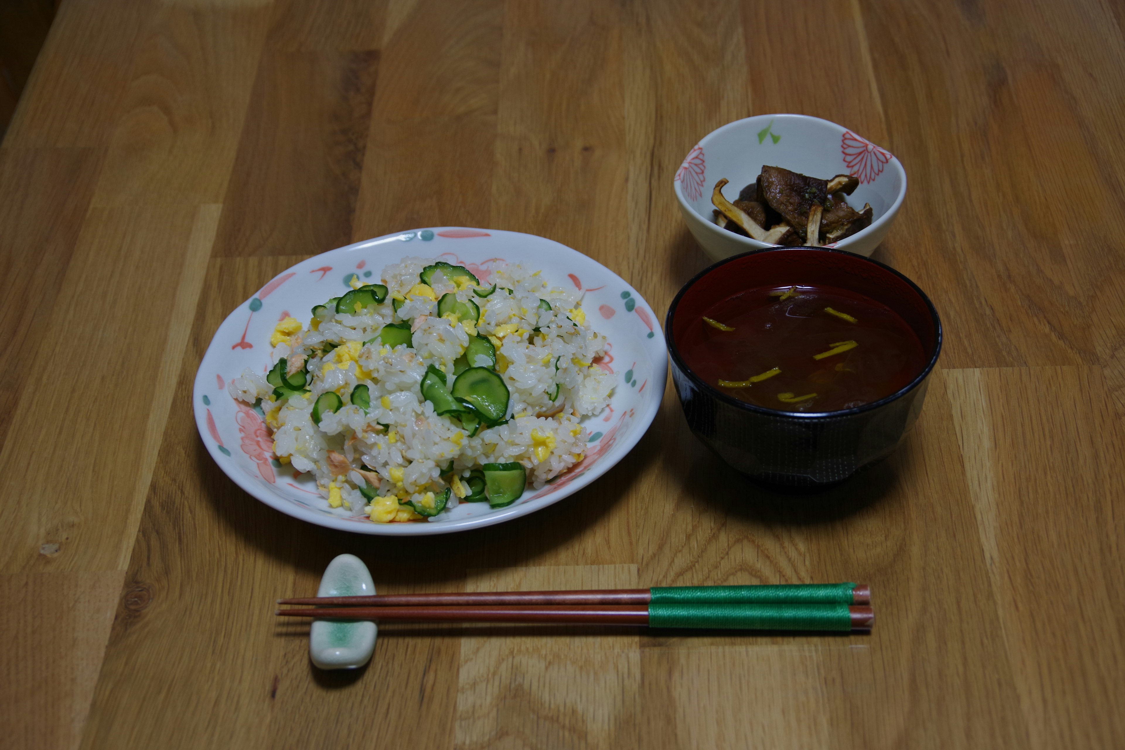 A Japanese meal featuring a plate of rice with vegetables and egg alongside miso soup and a small side dish