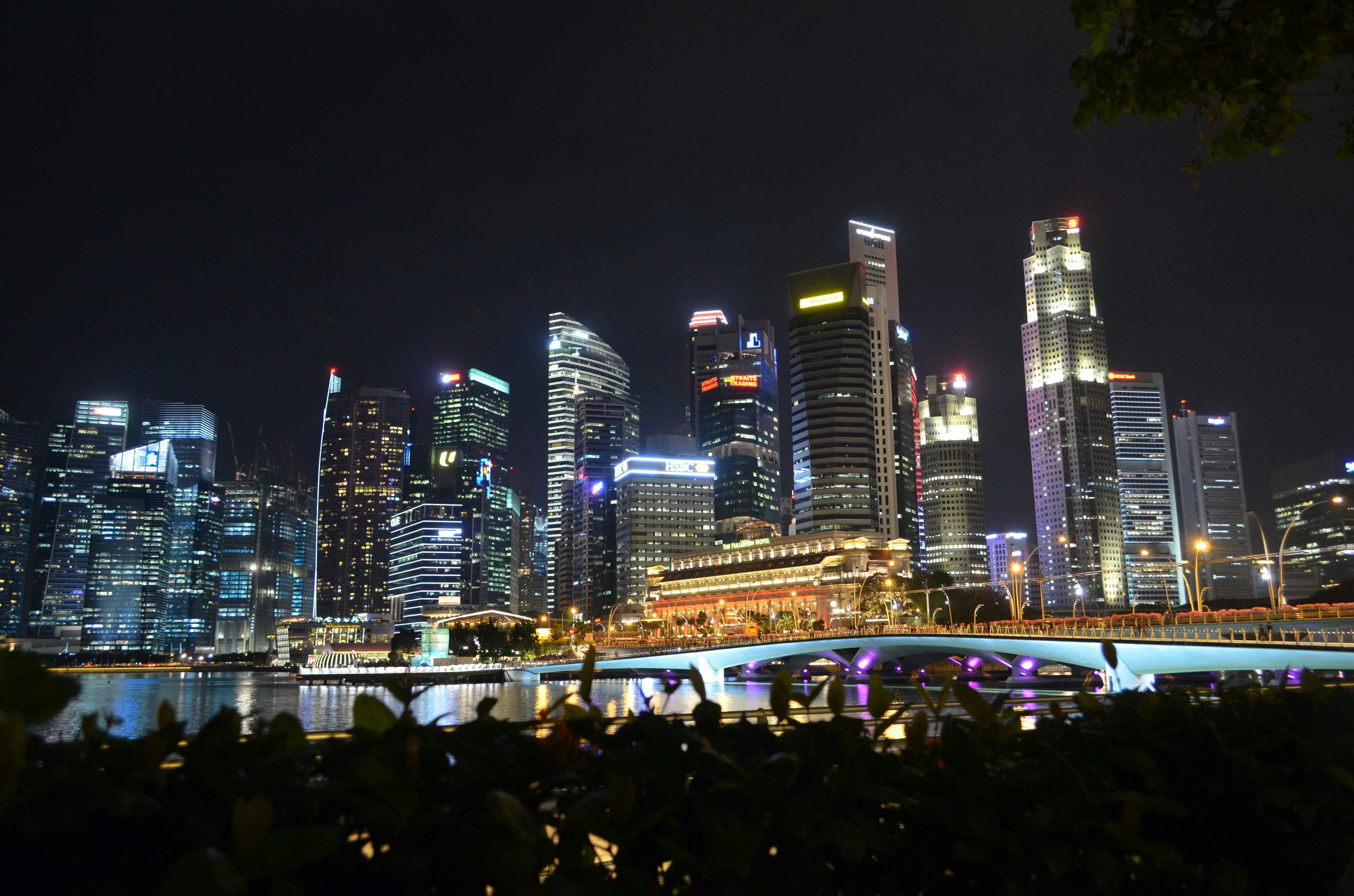 Singapore skyline at night with illuminated skyscrapers and a bridge