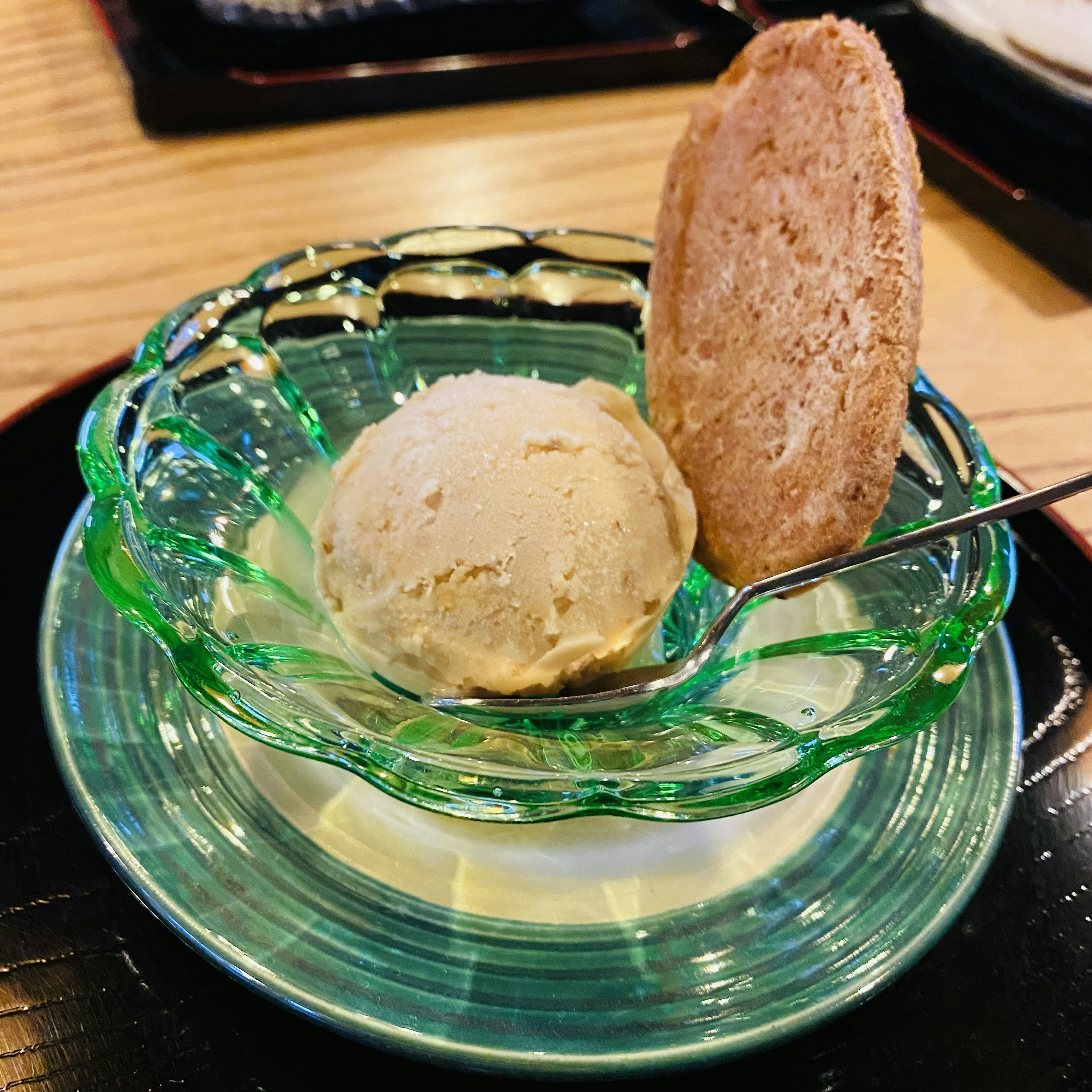 Crème glacée à la vanille servie dans un plat en verre vert avec un biscuit