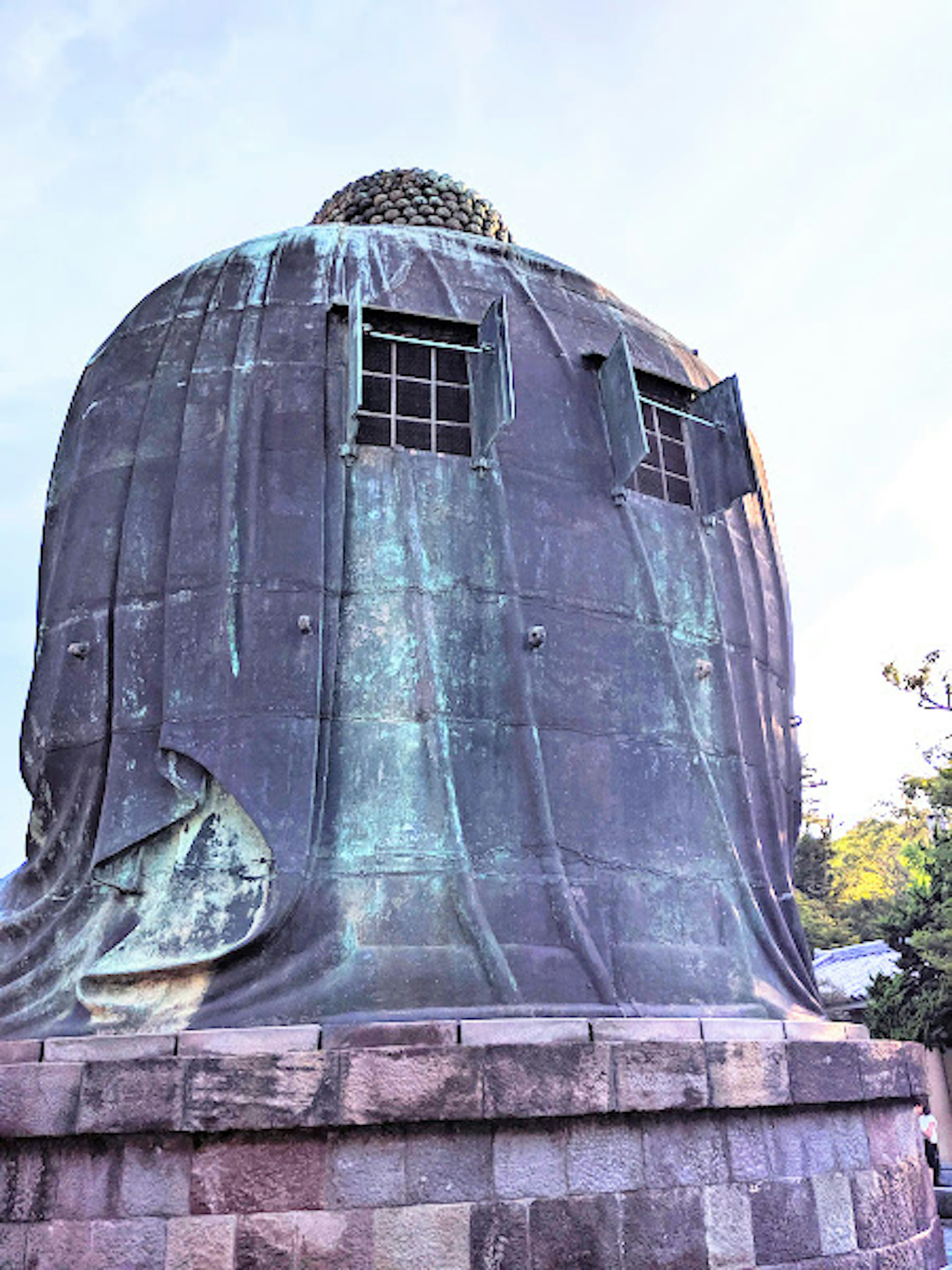 Rear view of a large bronze Buddha statue with visible windows