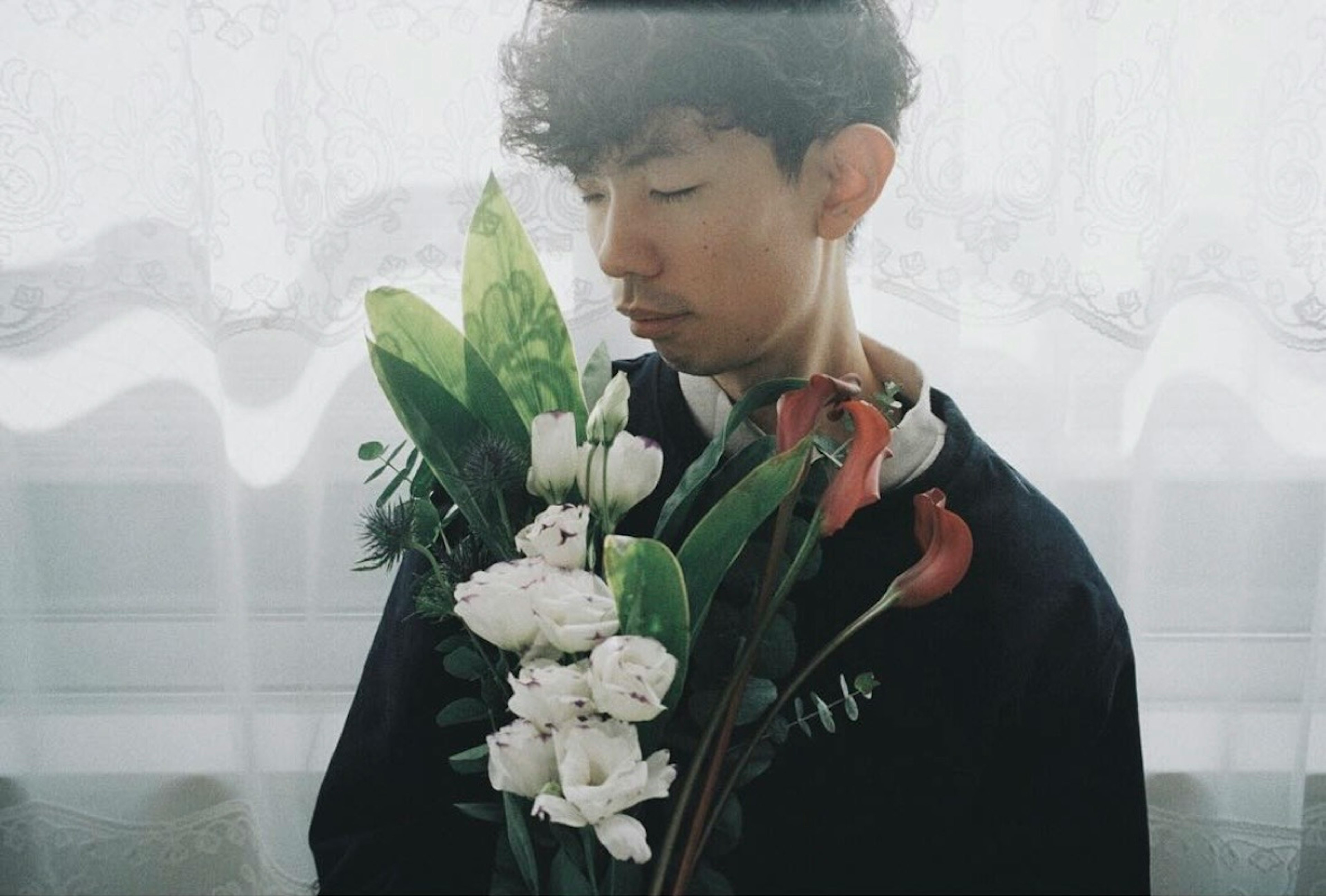 Retrato de un joven sosteniendo un ramo de flores Luz suave filtrándose a través de cortinas transparentes en el fondo