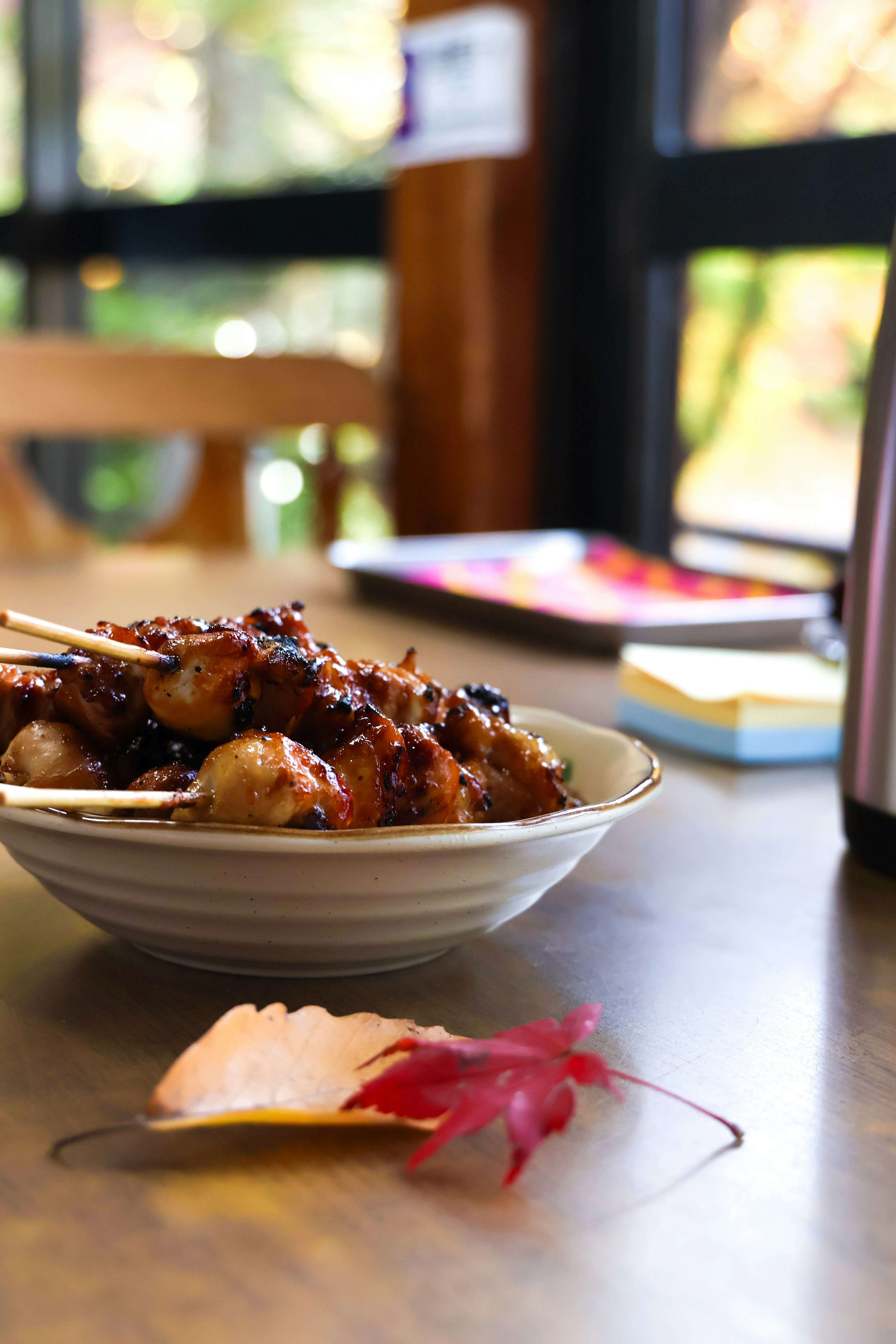 A bowl of teriyaki dango on a table with a maple leaf