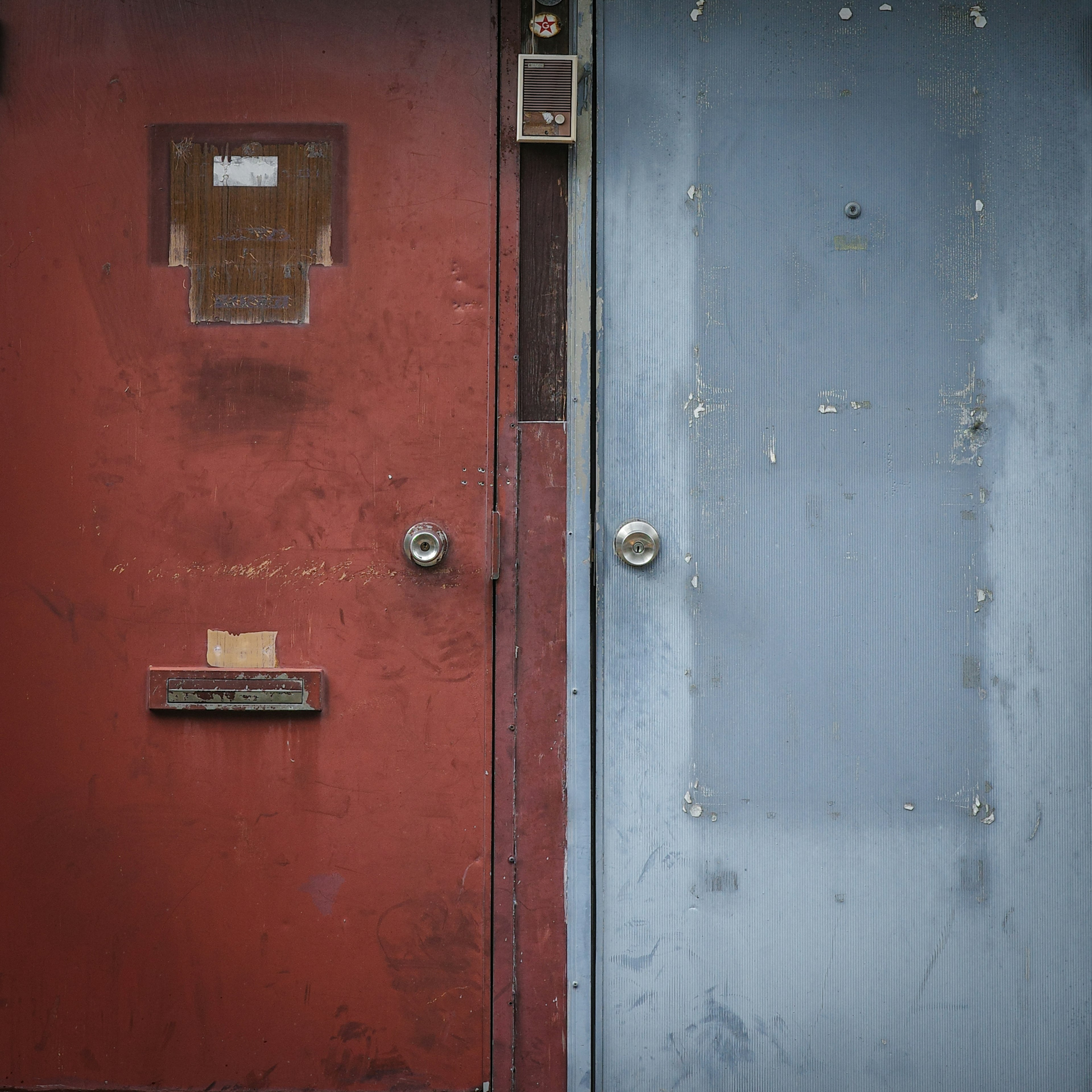 Una puerta roja y una puerta azul juntas con texturas desgastadas