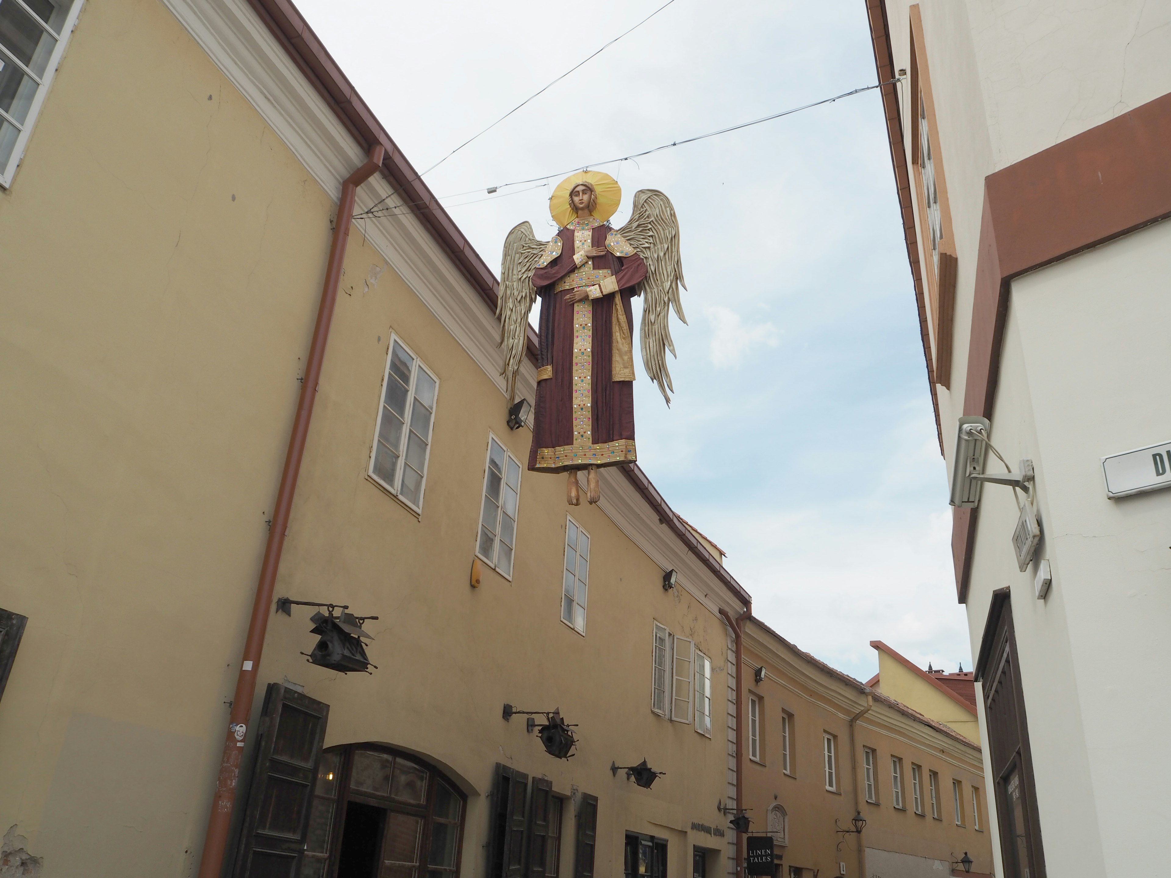 Statue d'ange suspendue au-dessus d'une rue Tenue colorée et halo doré