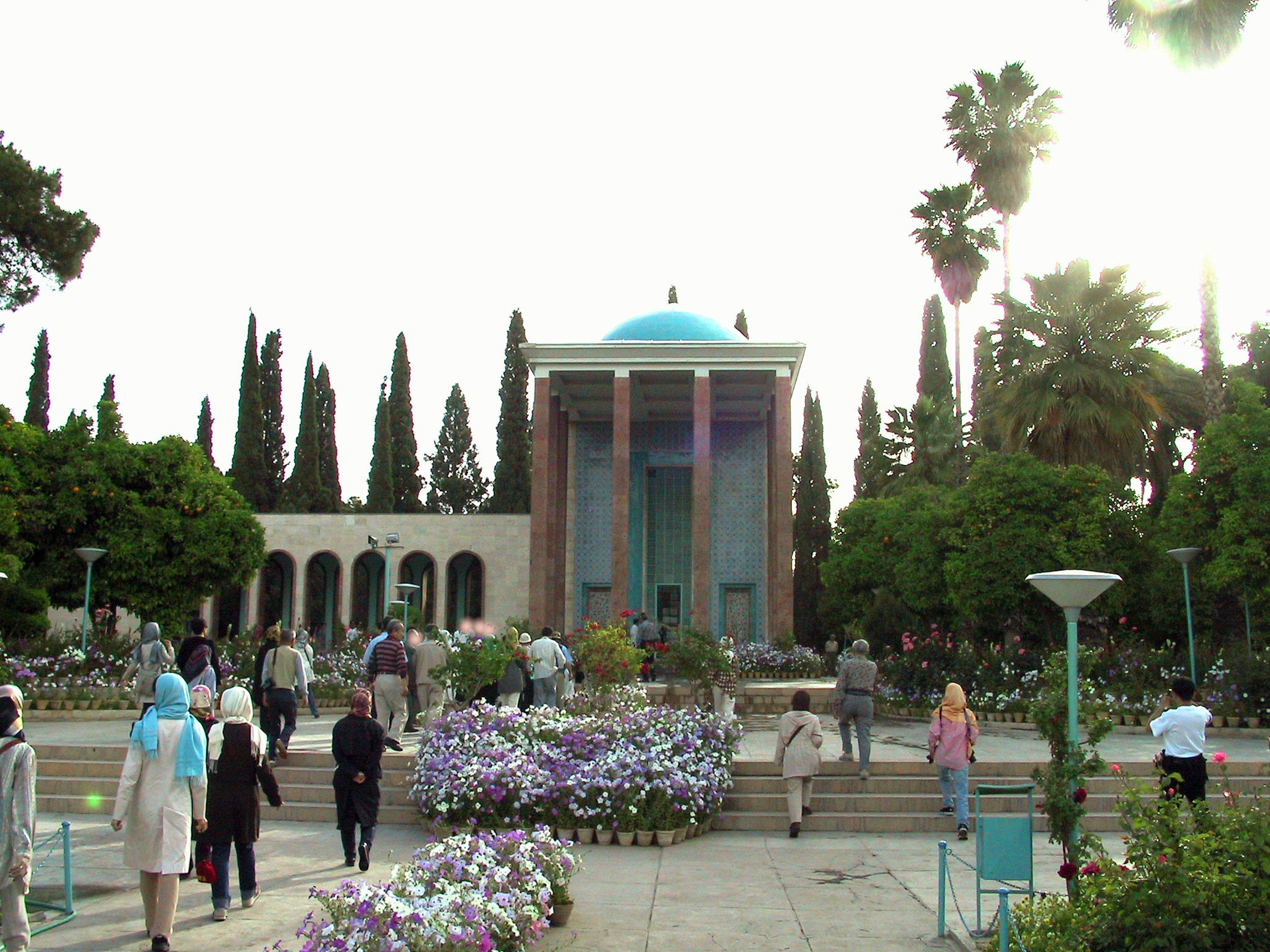 Visitors in a garden with a blue domed building and palm trees