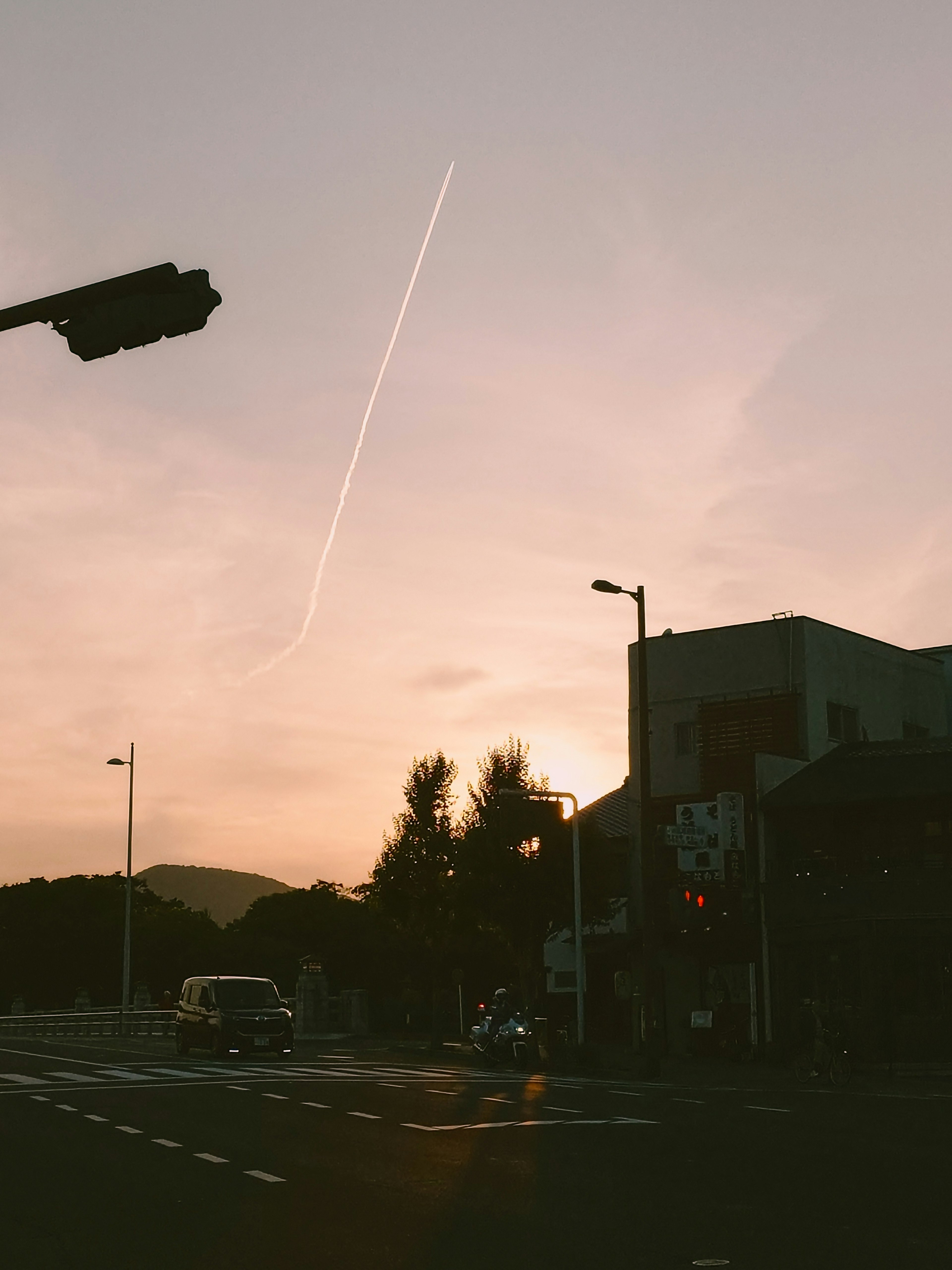 夕焼けの空に飛行機雲が見える街の交差点