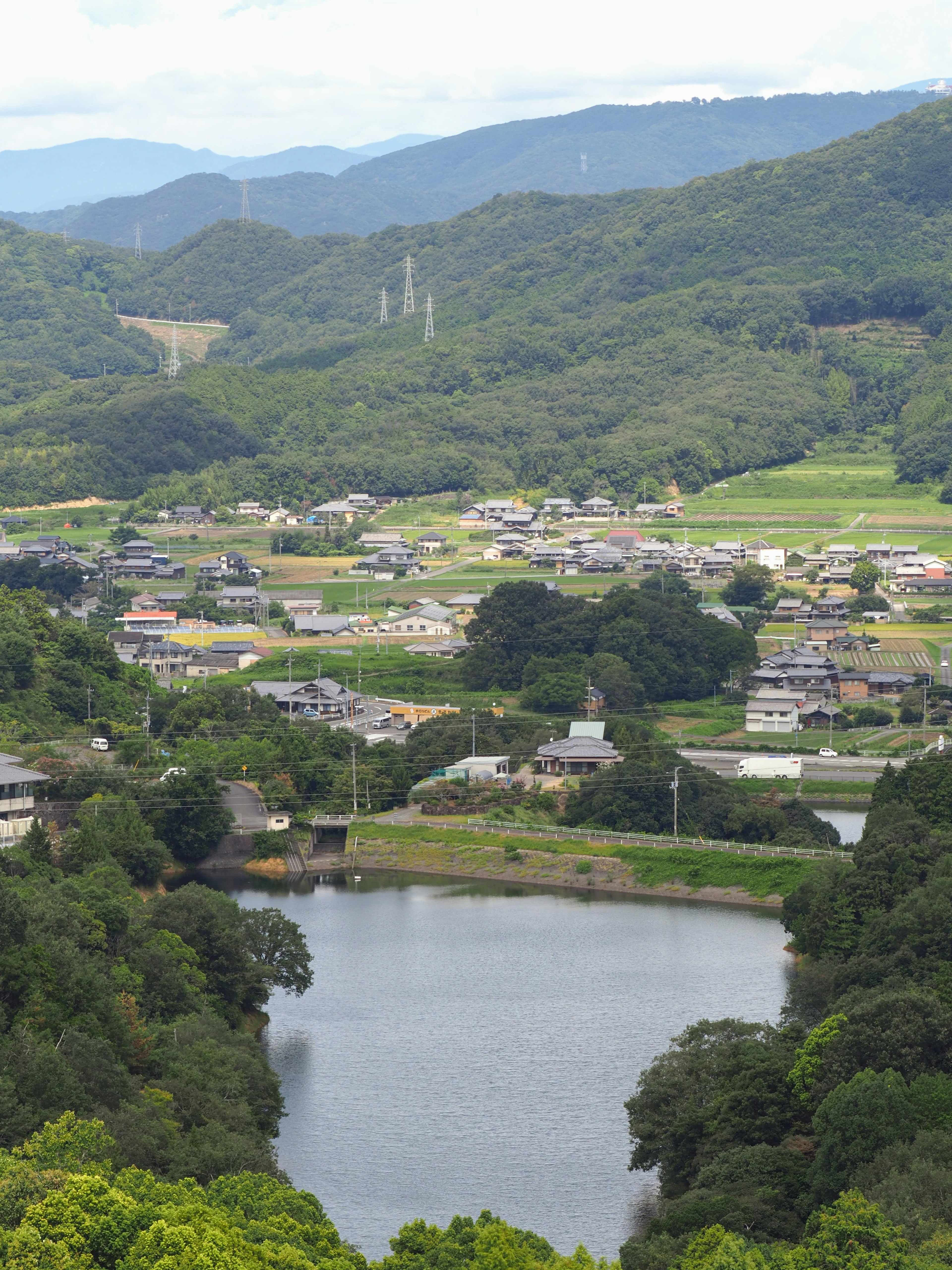 Paysage de montagnes verdoyantes et d'un lac serein avec un village rural