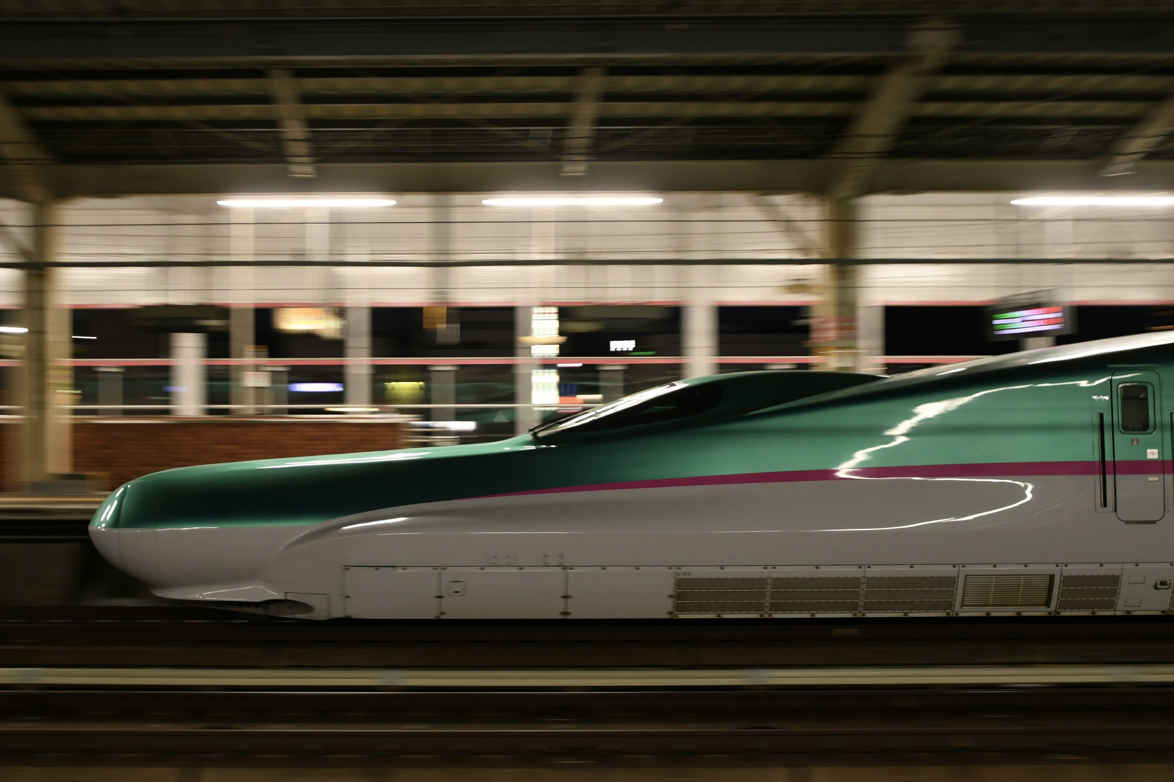 Shinkansen passing through a station at night