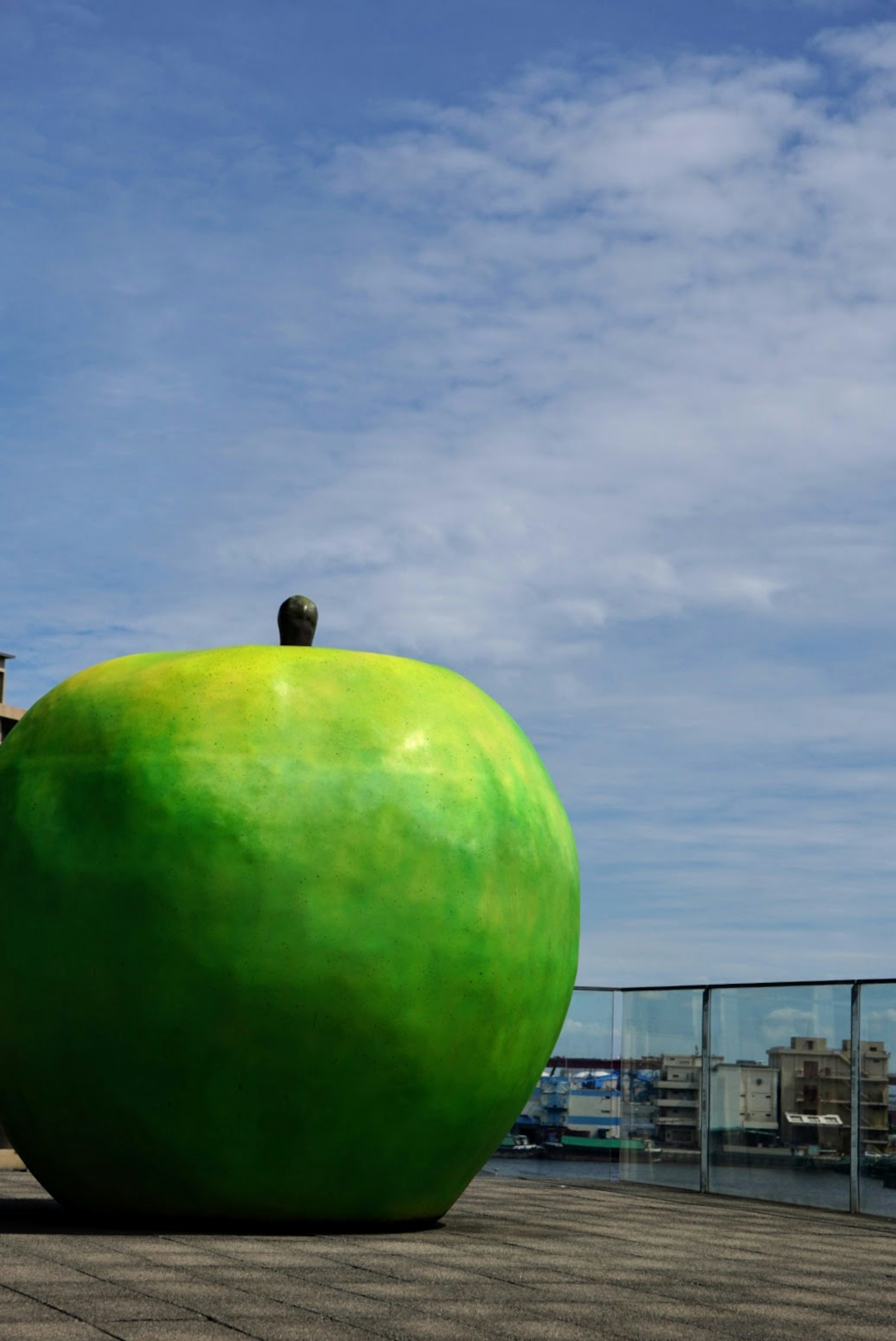 Una grande scultura di mela verde si erge sotto un cielo blu