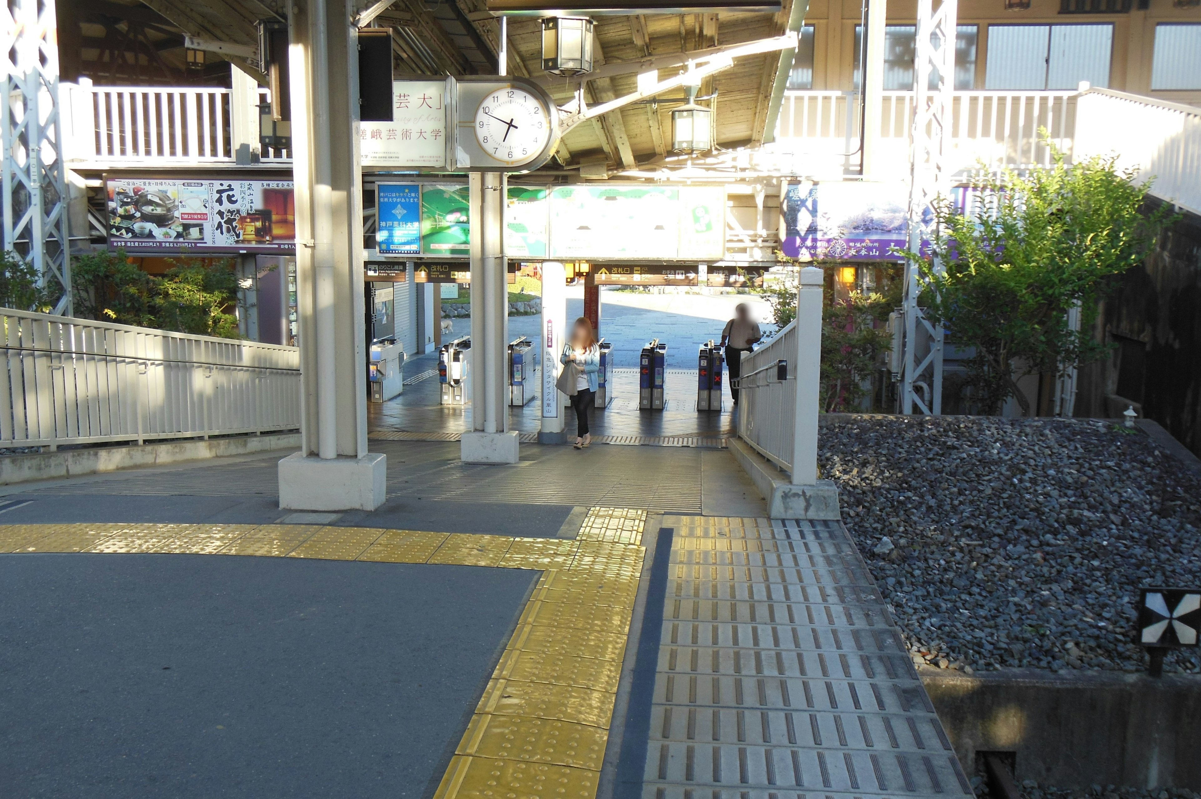 View of a train station platform featuring a clock and people