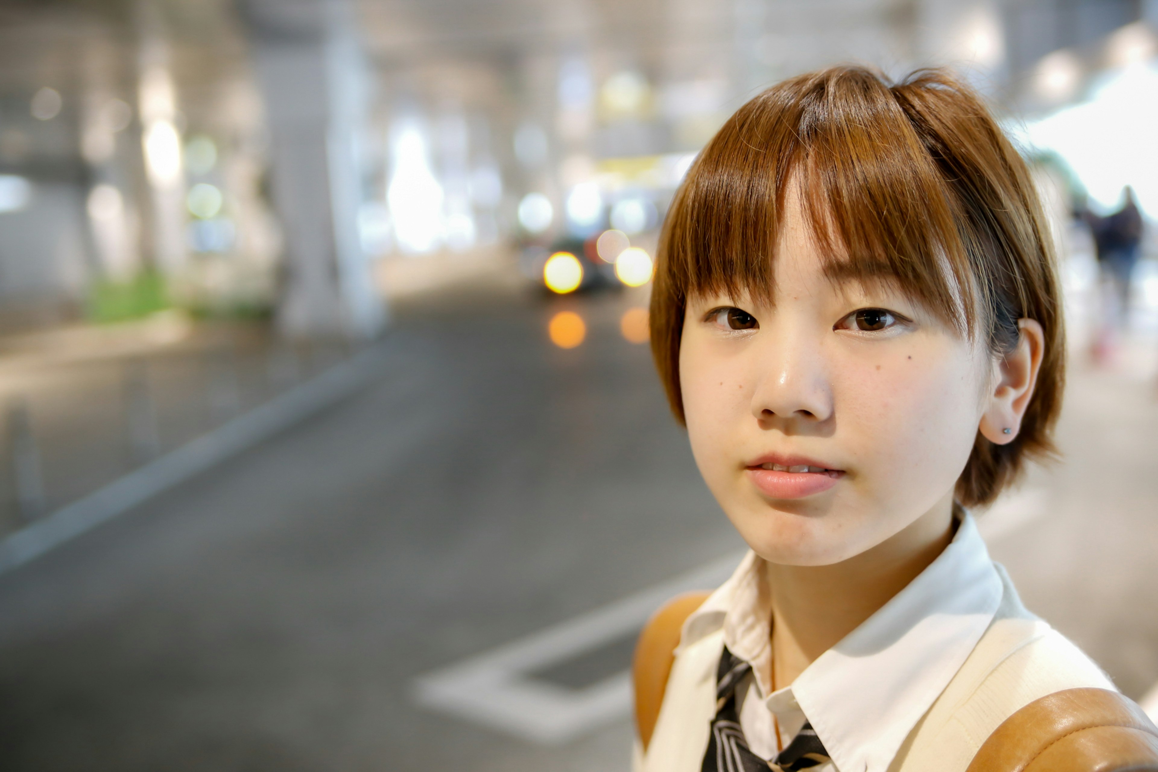 Portrait of a young woman smiling at a station with a blurred urban background