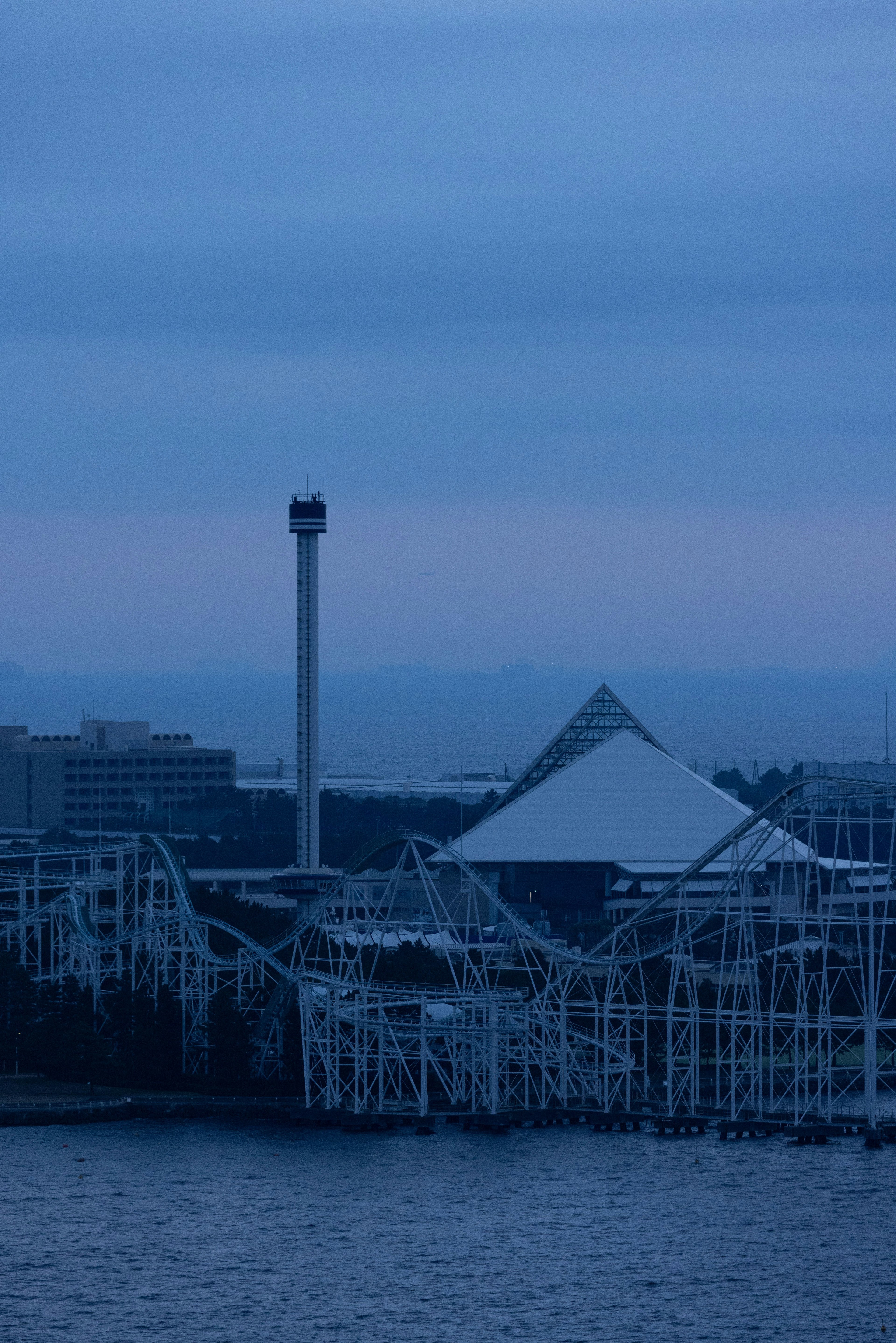 Parc d'attractions avec une grande roue et un bâtiment en forme de pyramide sous un ciel bleu