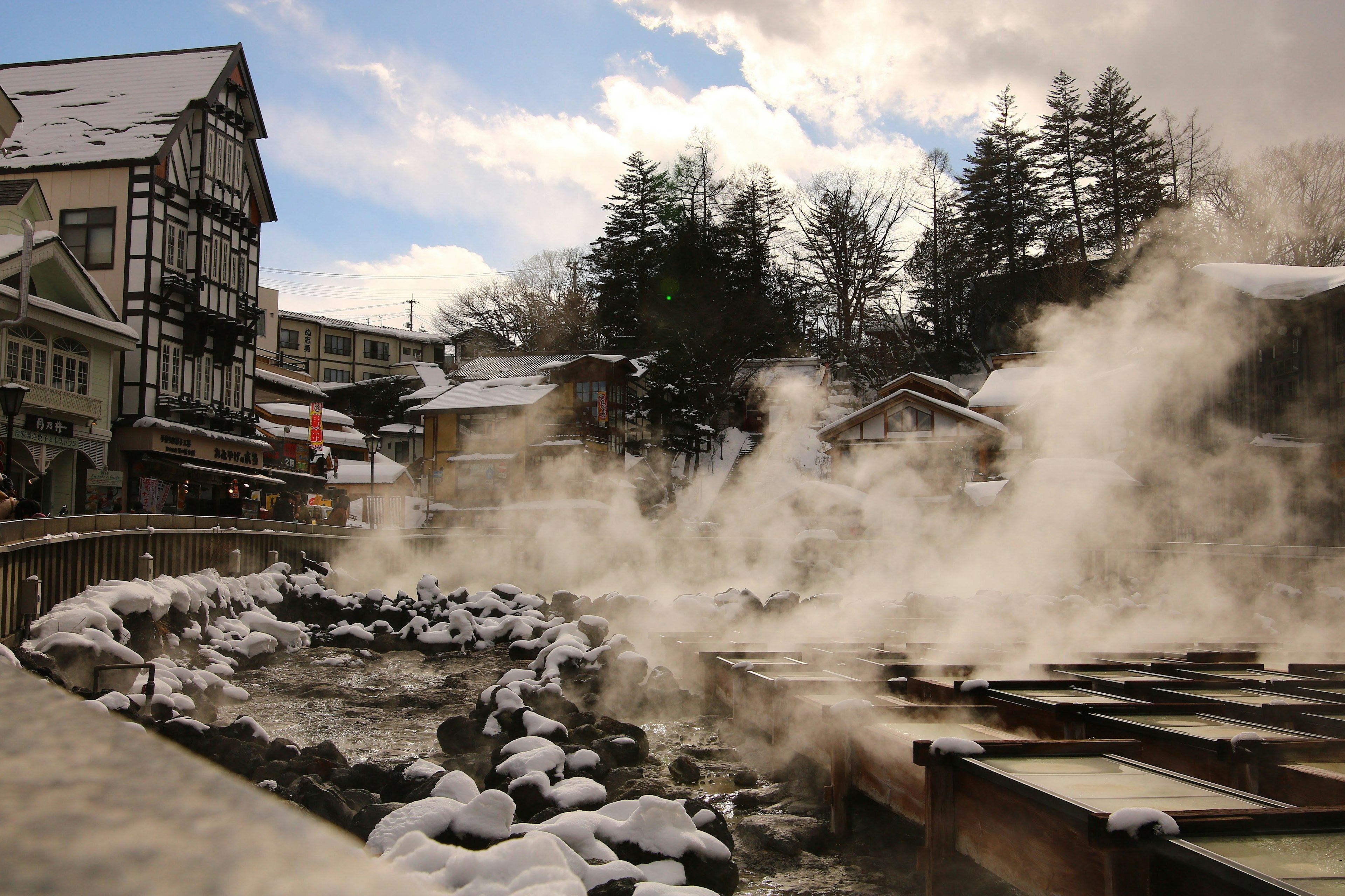 Scenic view of a snowy hot spring town with rising steam