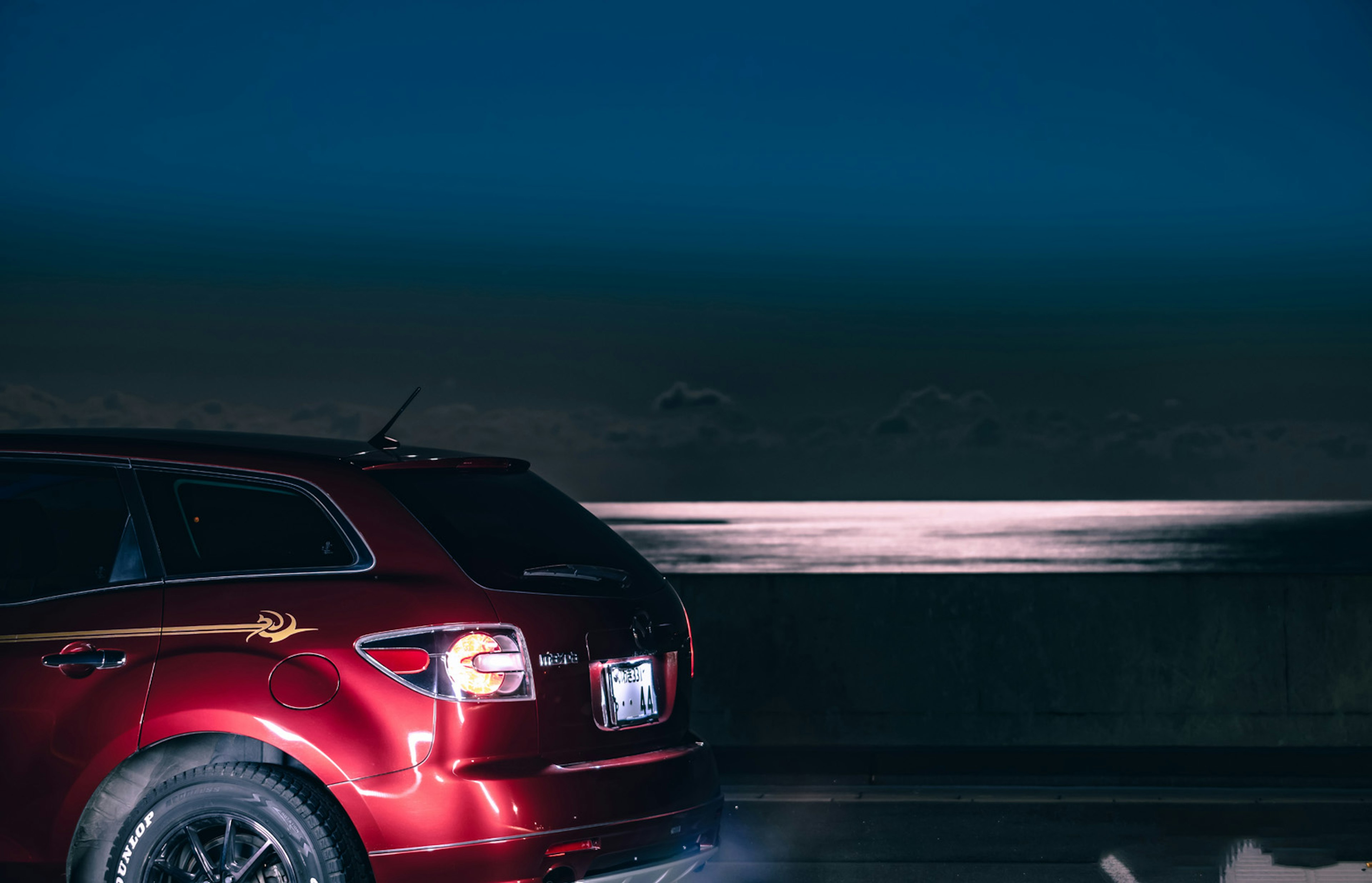 Red SUV driving along a nighttime coast