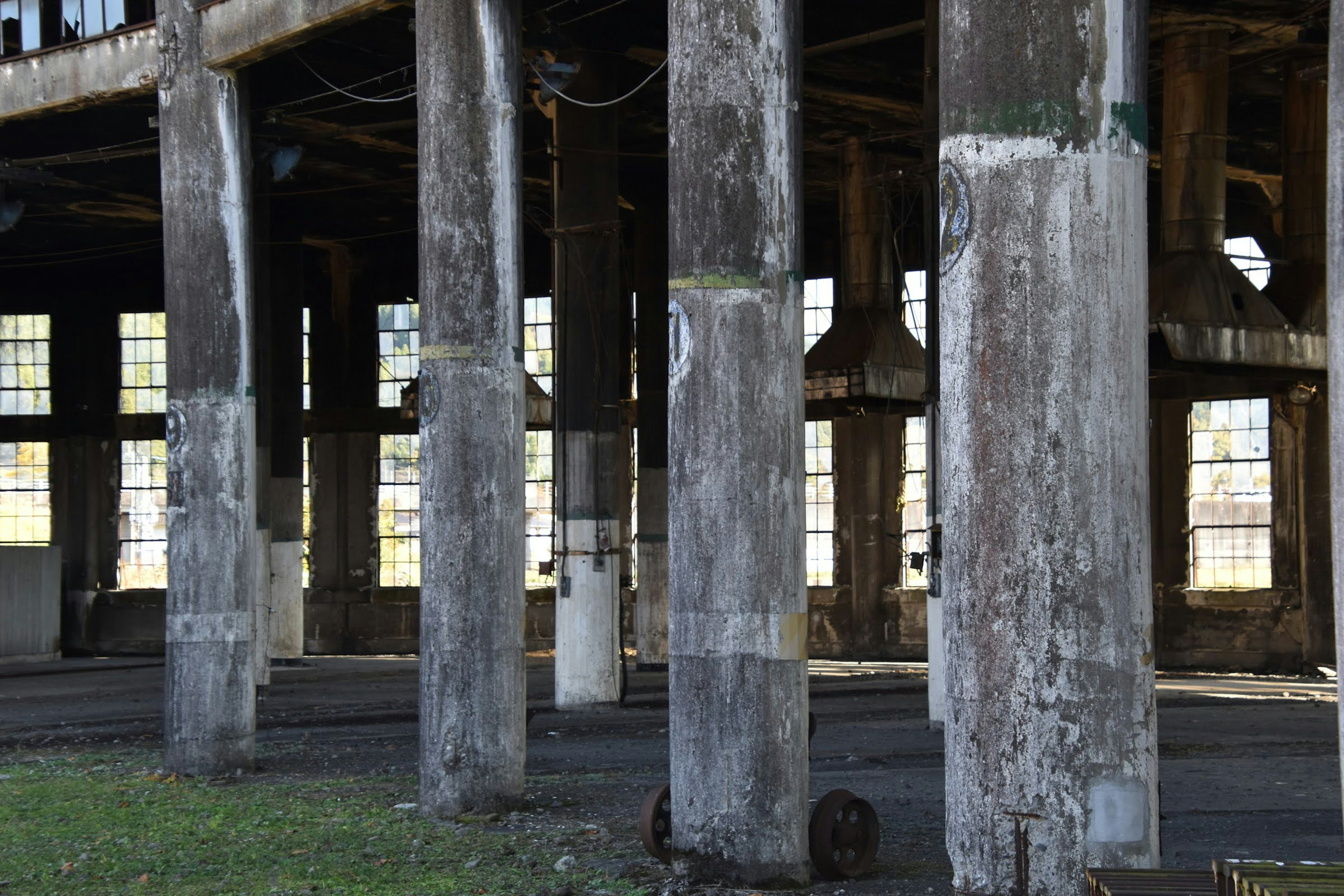 Interior view of an old factory featuring weathered columns and large windows