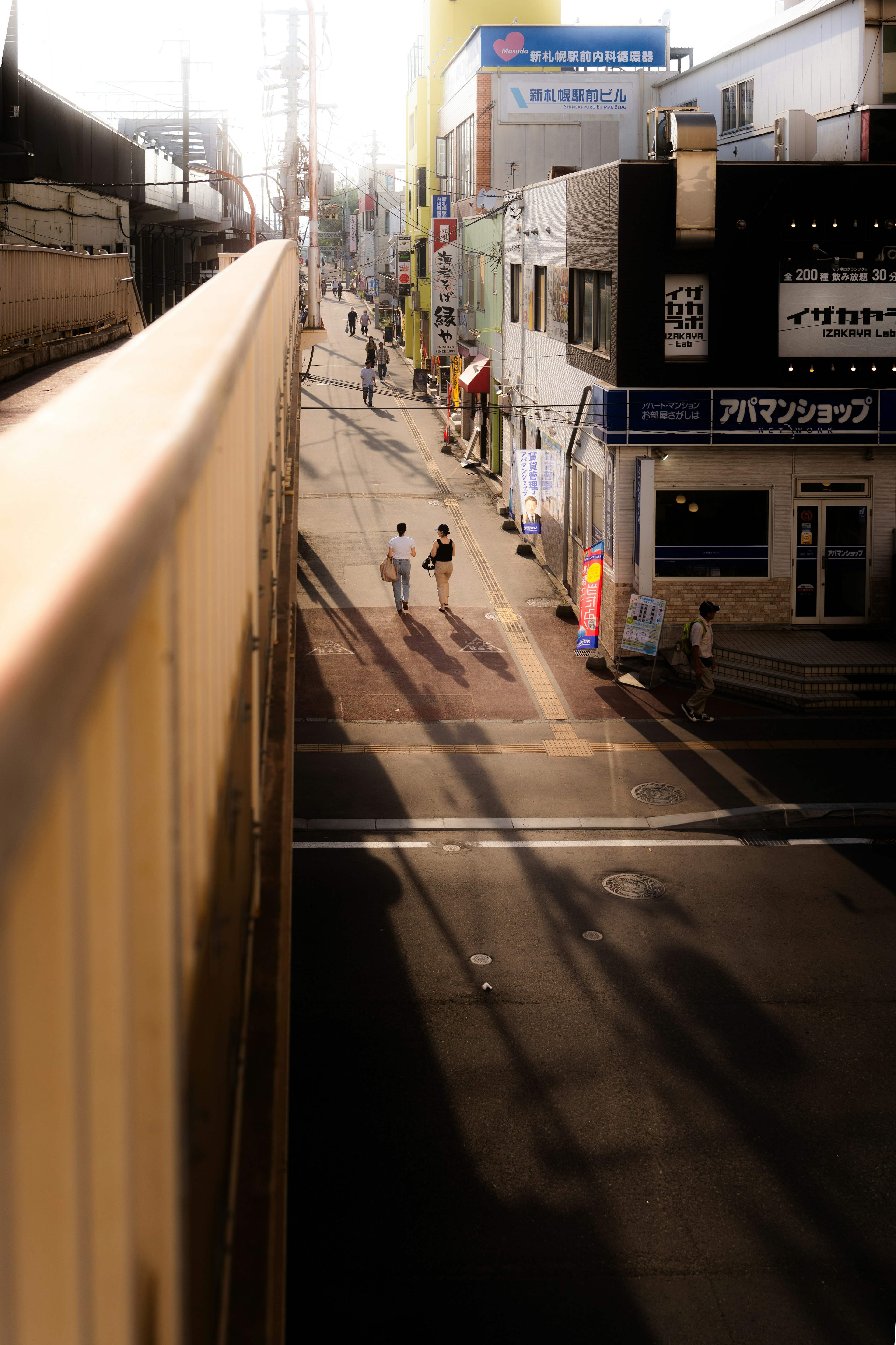 街の風景に人々が歩いている様子と影が見える