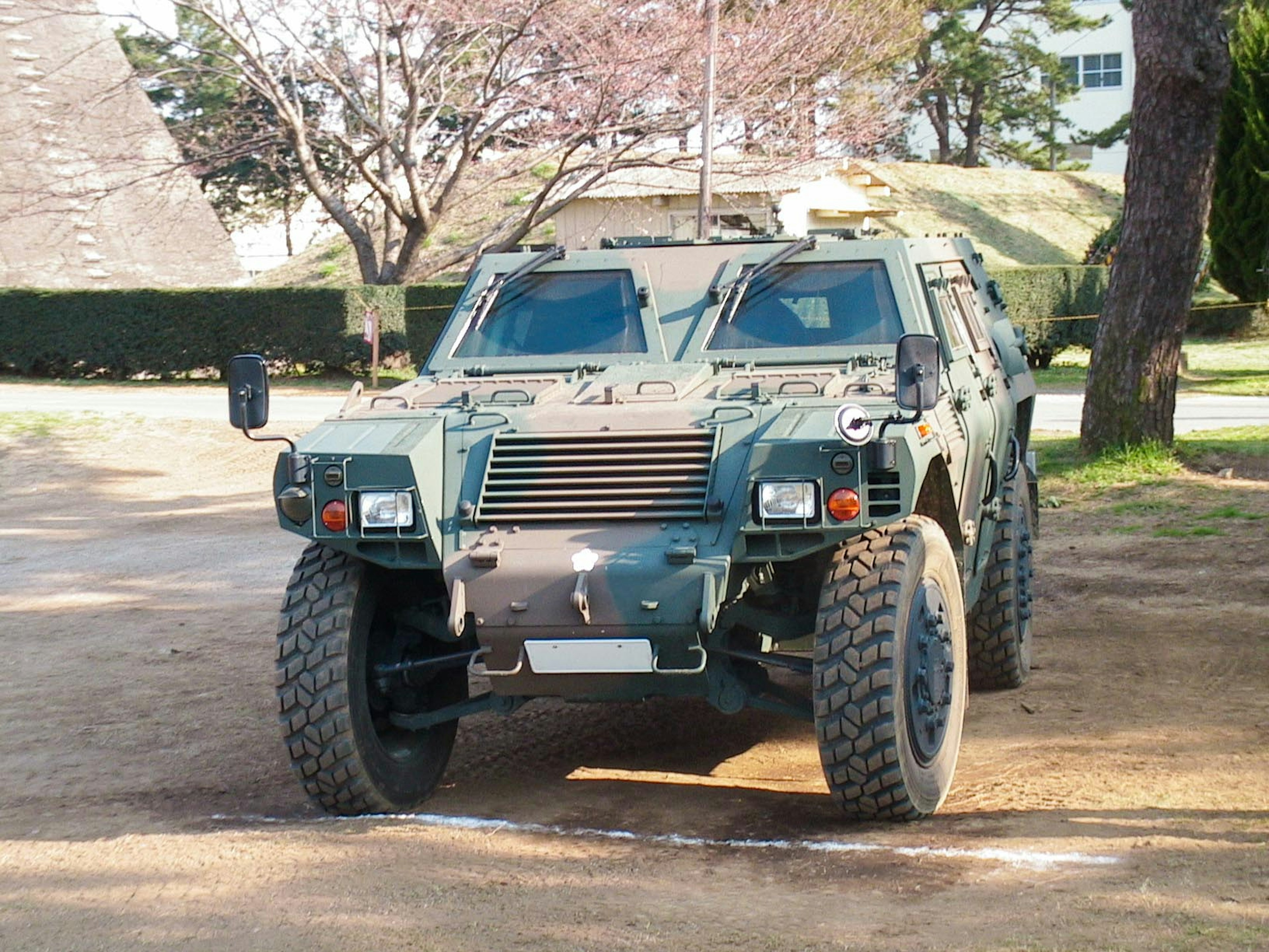 Green armored vehicle parked on dirt in a park