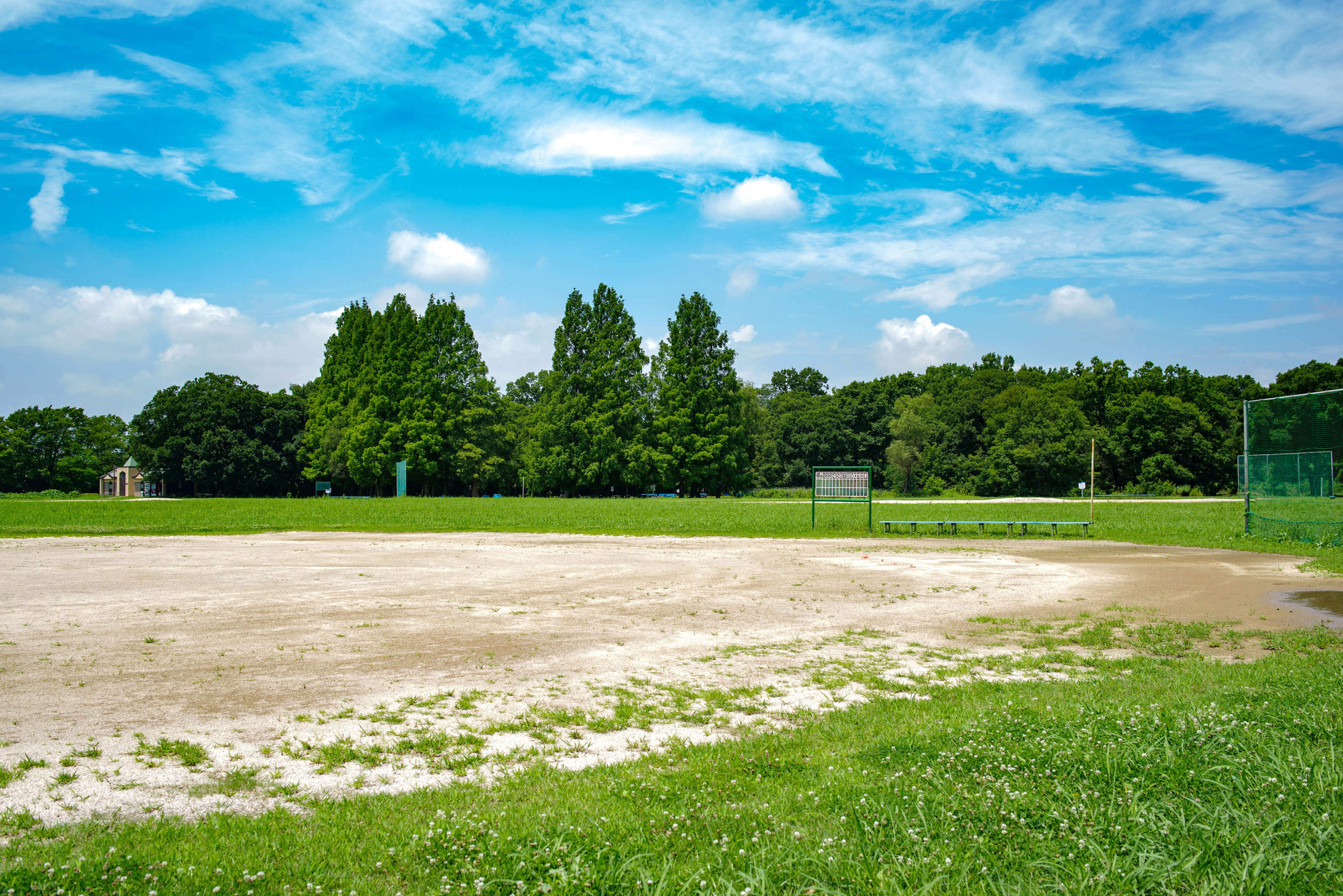 Baseballfeld unter blauem Himmel Gras und Erde