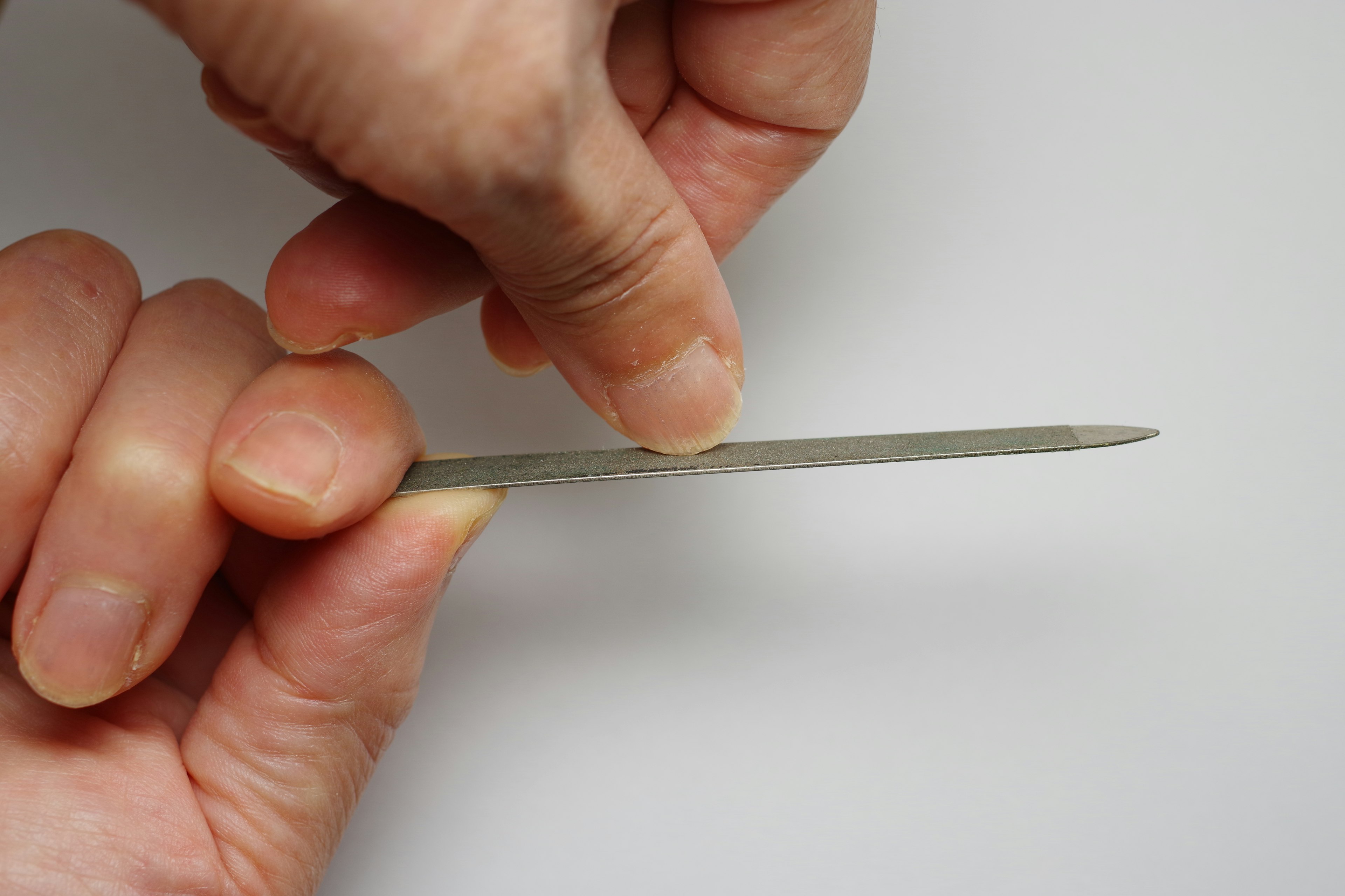 A person holding a metal flat file with both hands