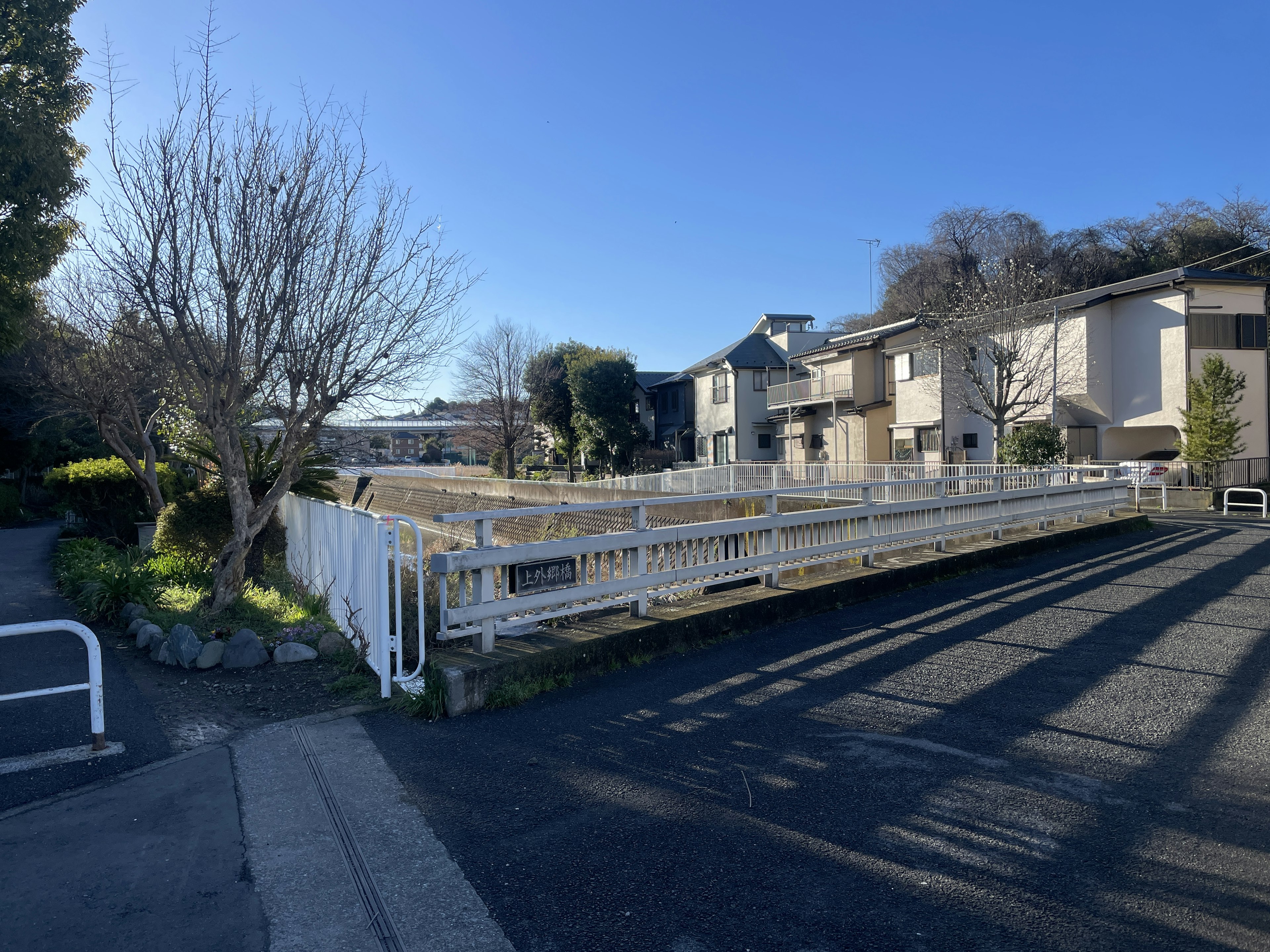 Residential street view with white fence and trees