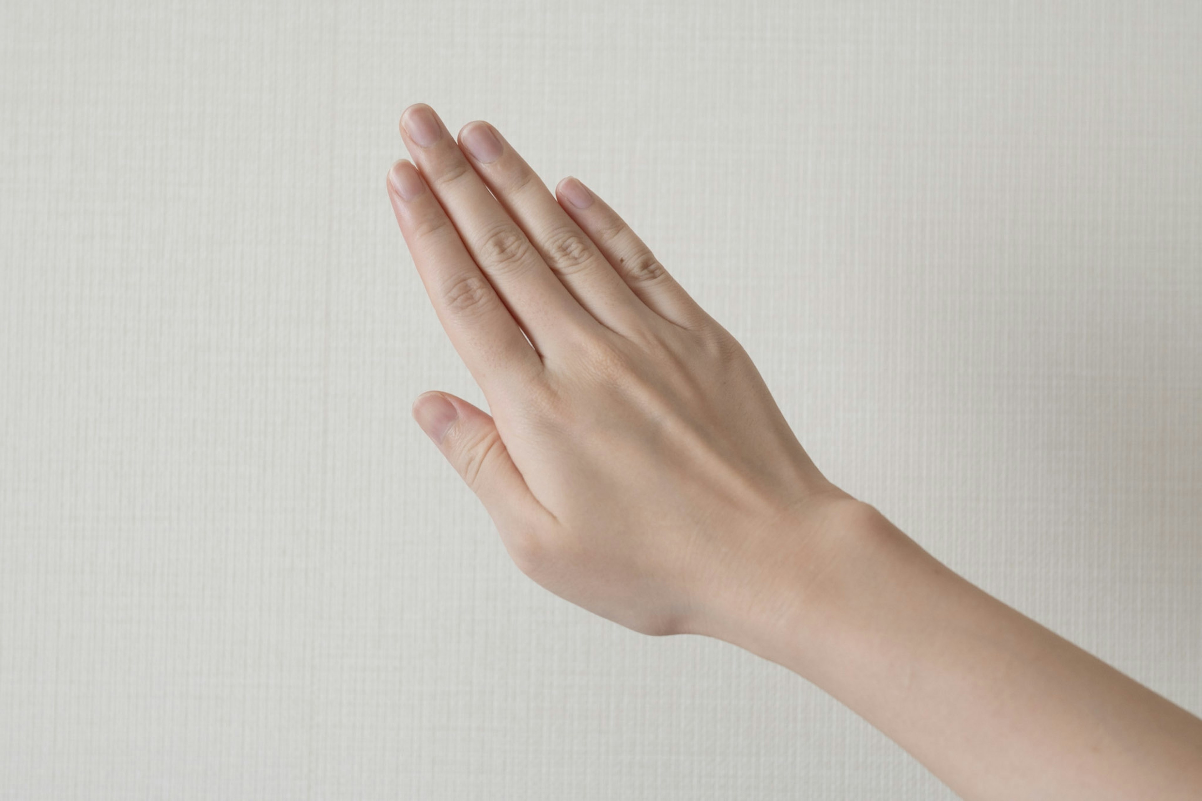 Una mano con la palma hacia arriba alcanzando una pared blanca