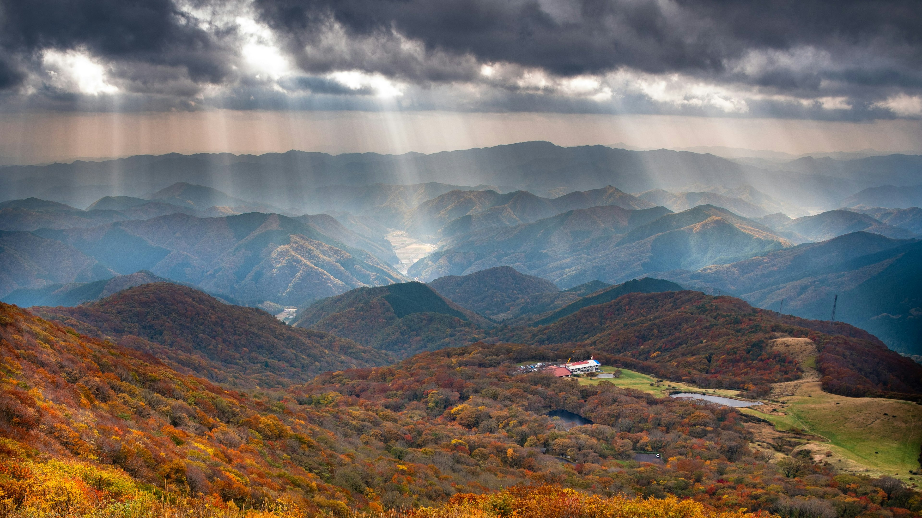 Bellissimo paesaggio di montagne colorate d'autunno con raggi di luce che penetrano nella nebbia