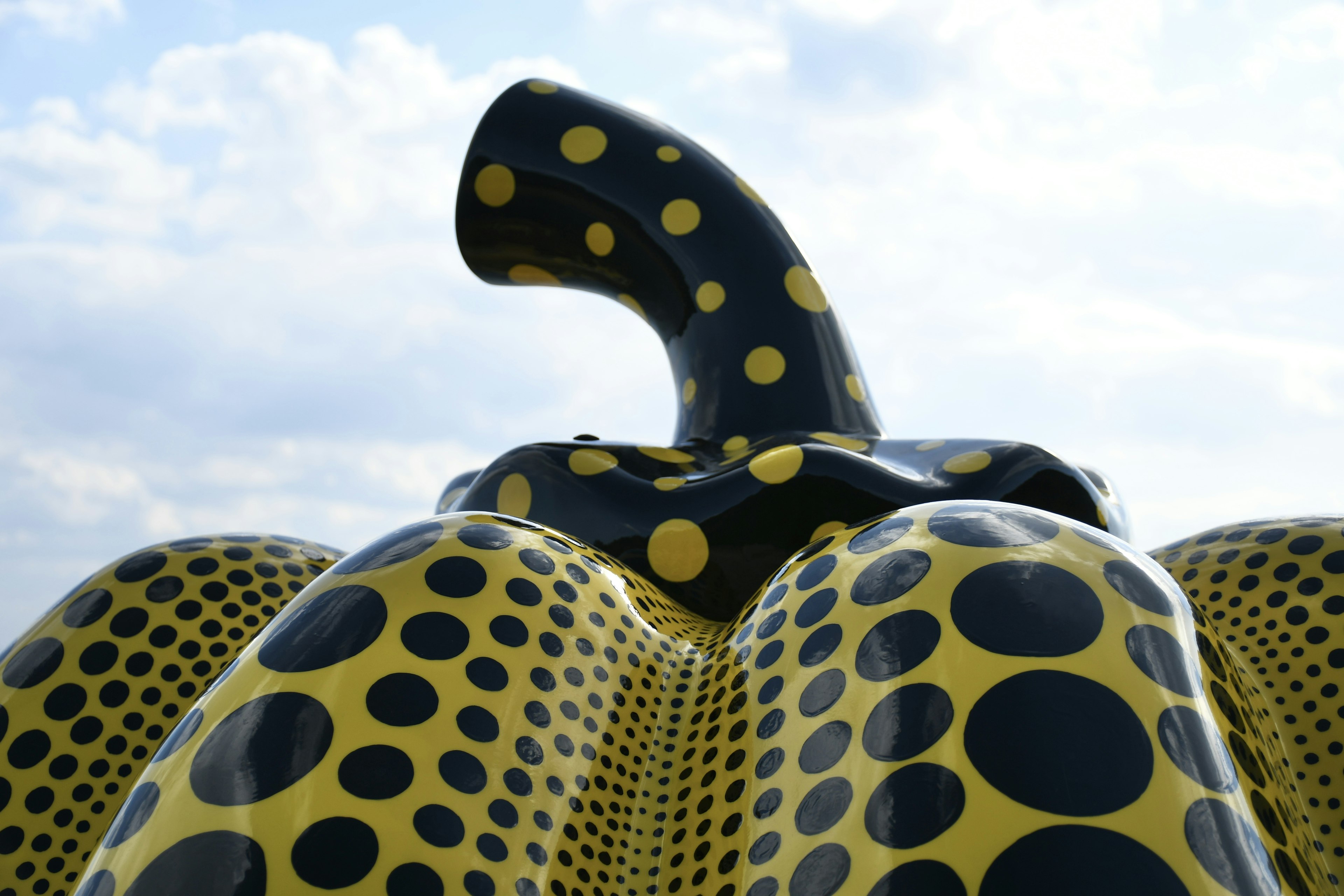 Vista superior de una escultura de calabaza con lunares negros y amarillos contra un cielo nublado