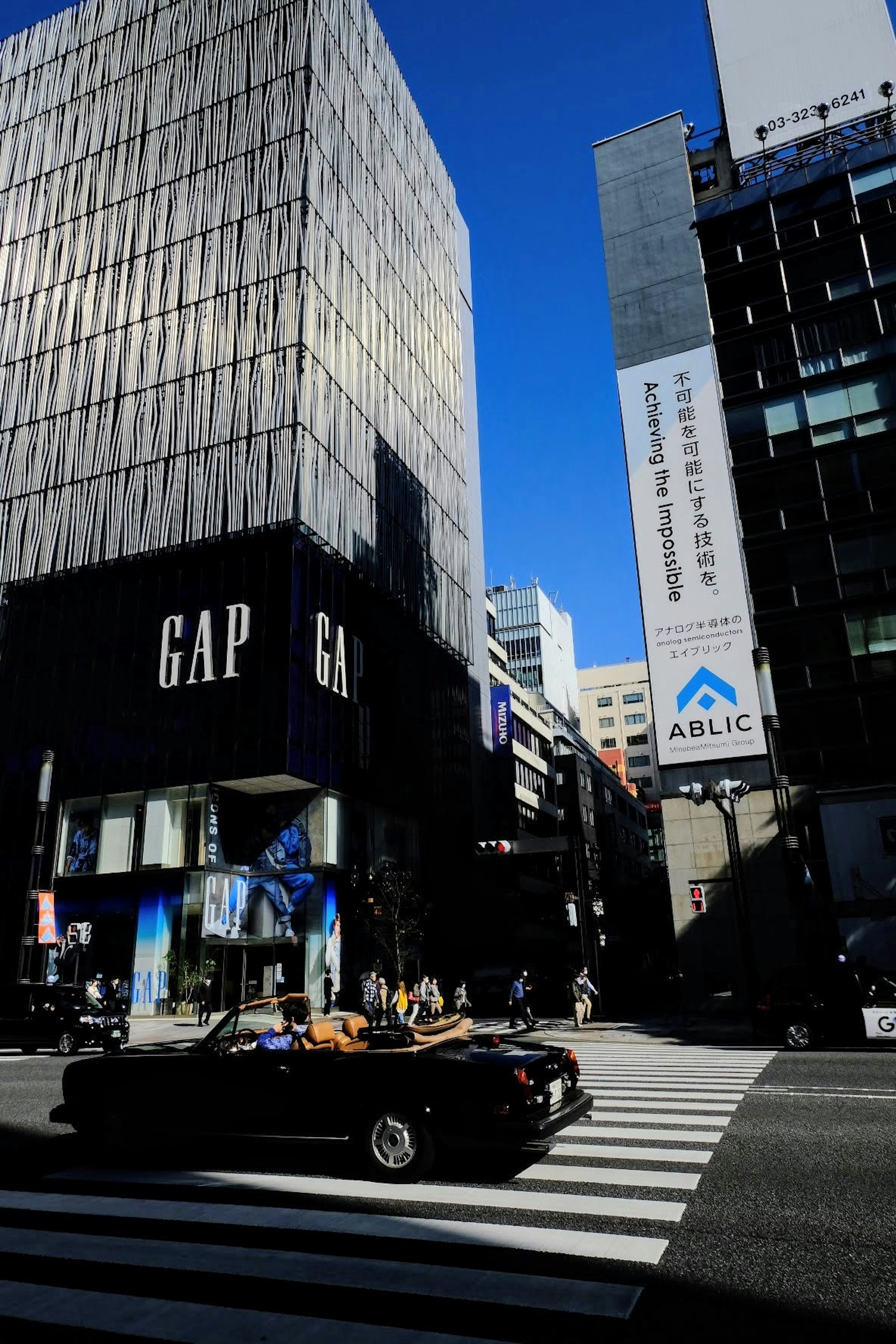 GAP store with a car crossing the intersection under a blue sky