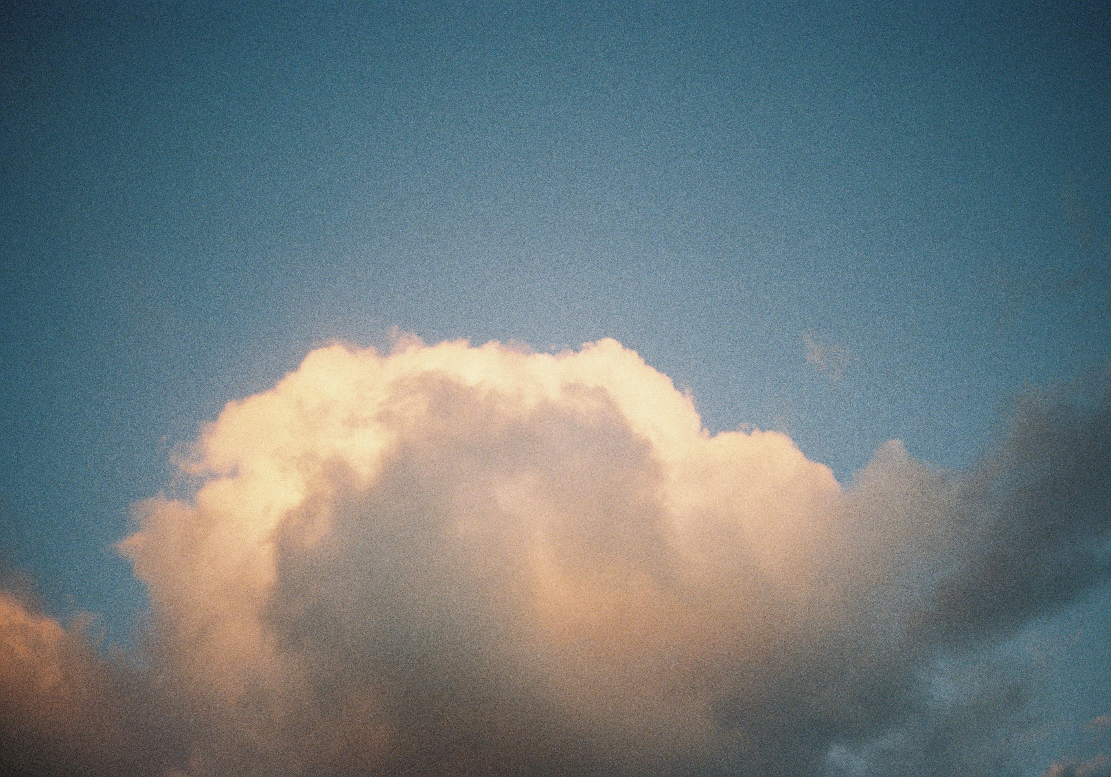 Weiche Wolke, beleuchtet von orangefarbenem Licht gegen einen blauen Himmel