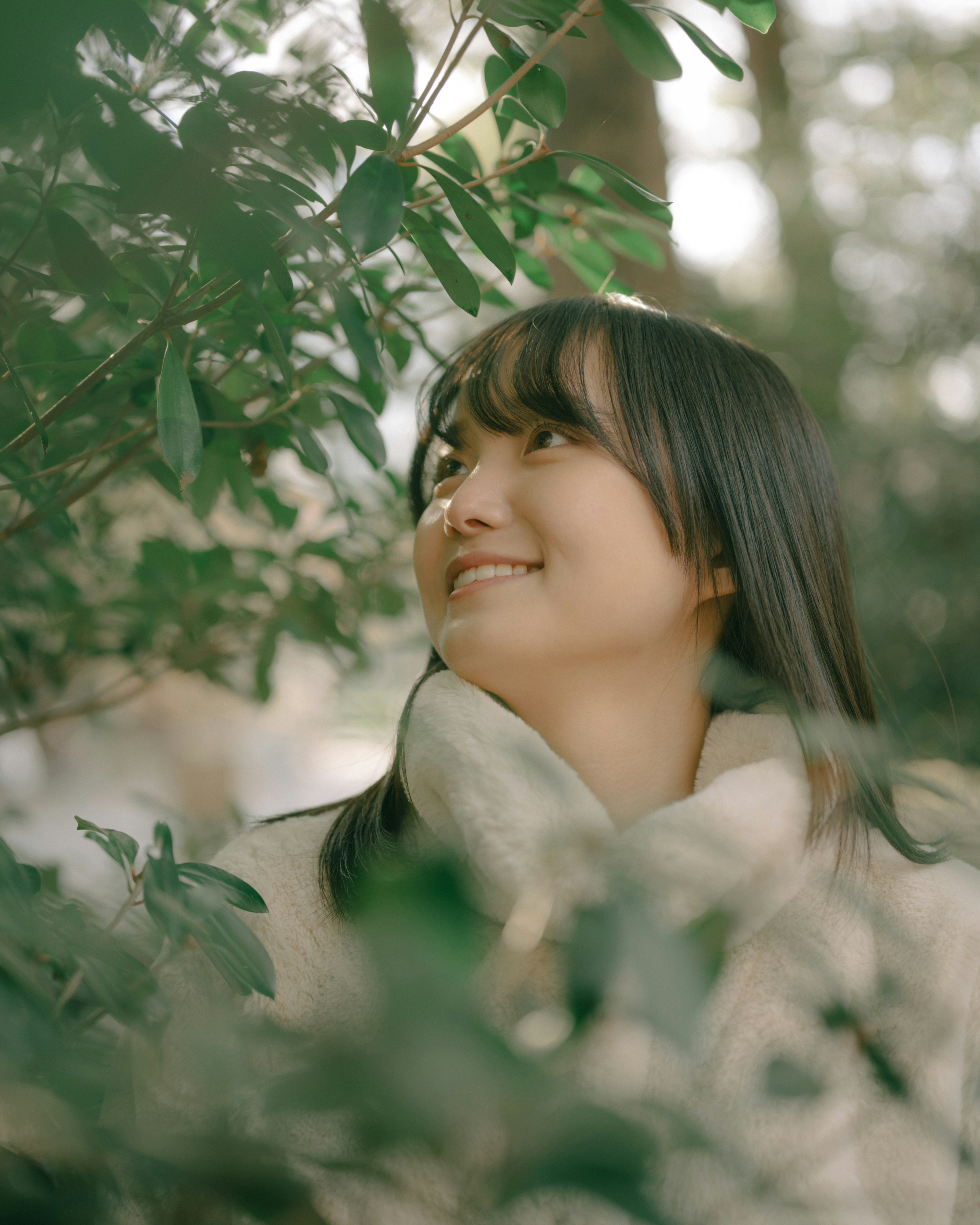 緑の葉の間から微笑む女性のポートレート